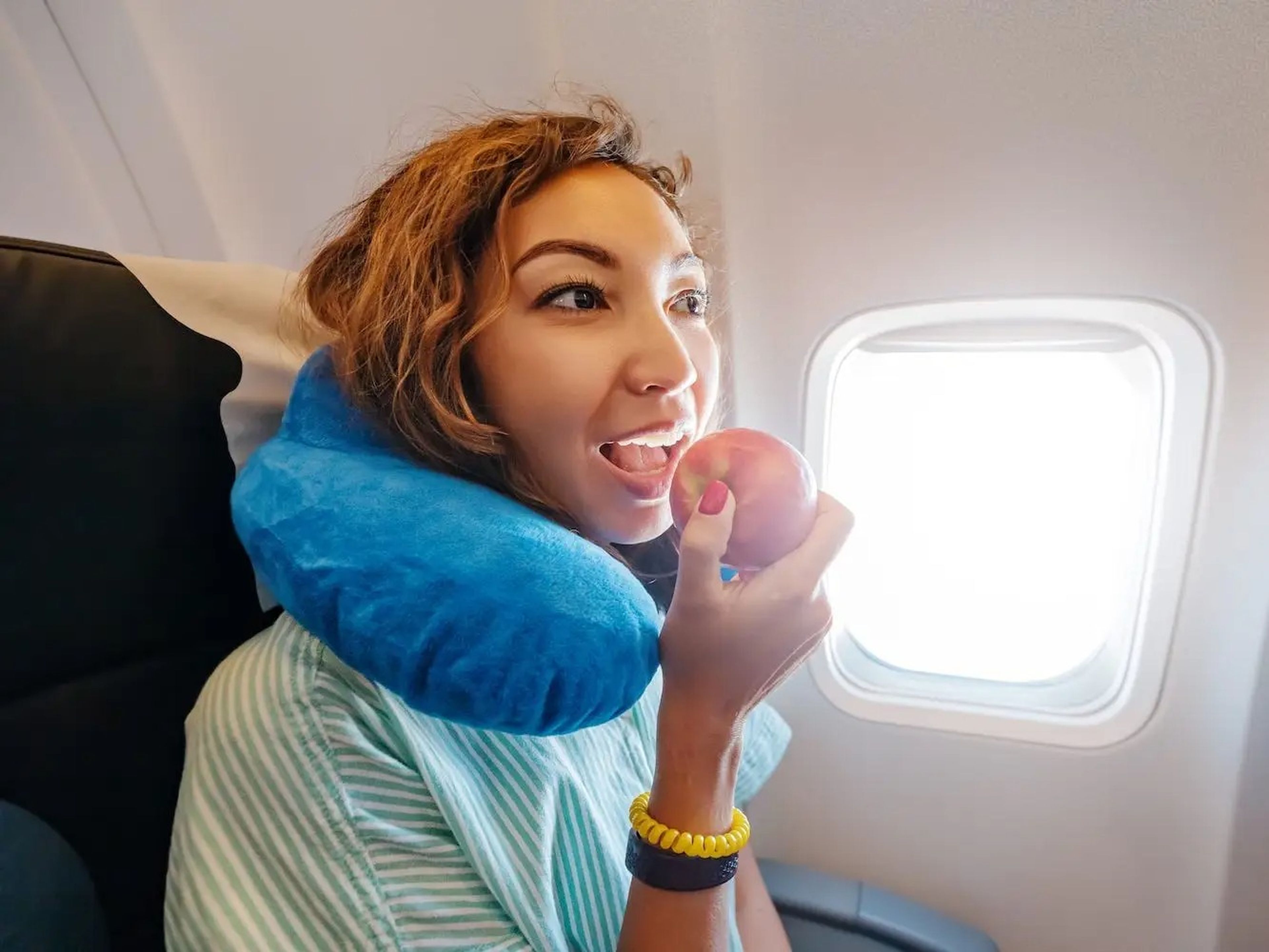 A woman eats an apple on an airplane.