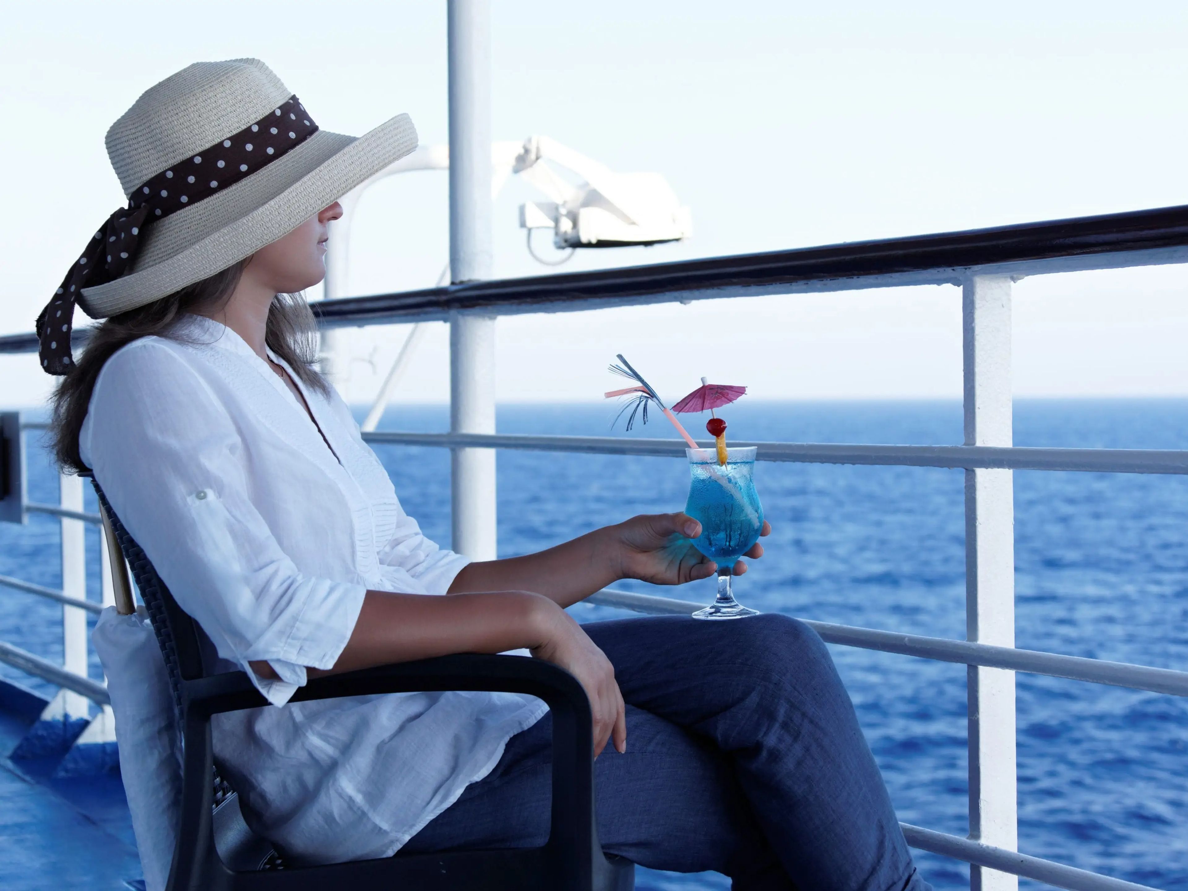 Woman sitting on the balcony of a cruise ship holding a tropical drink