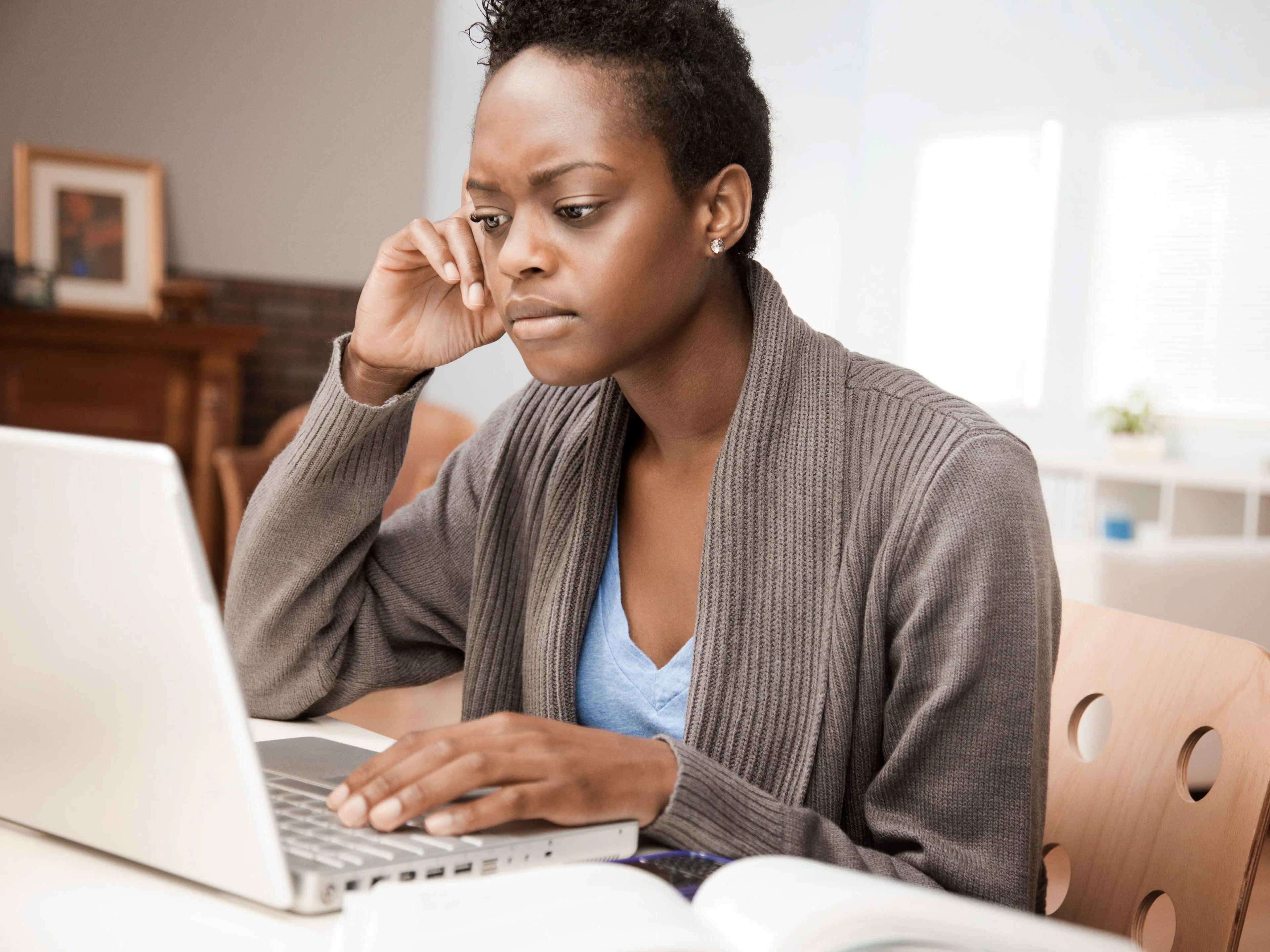 Woman thinking, might be confused, while working on laptop