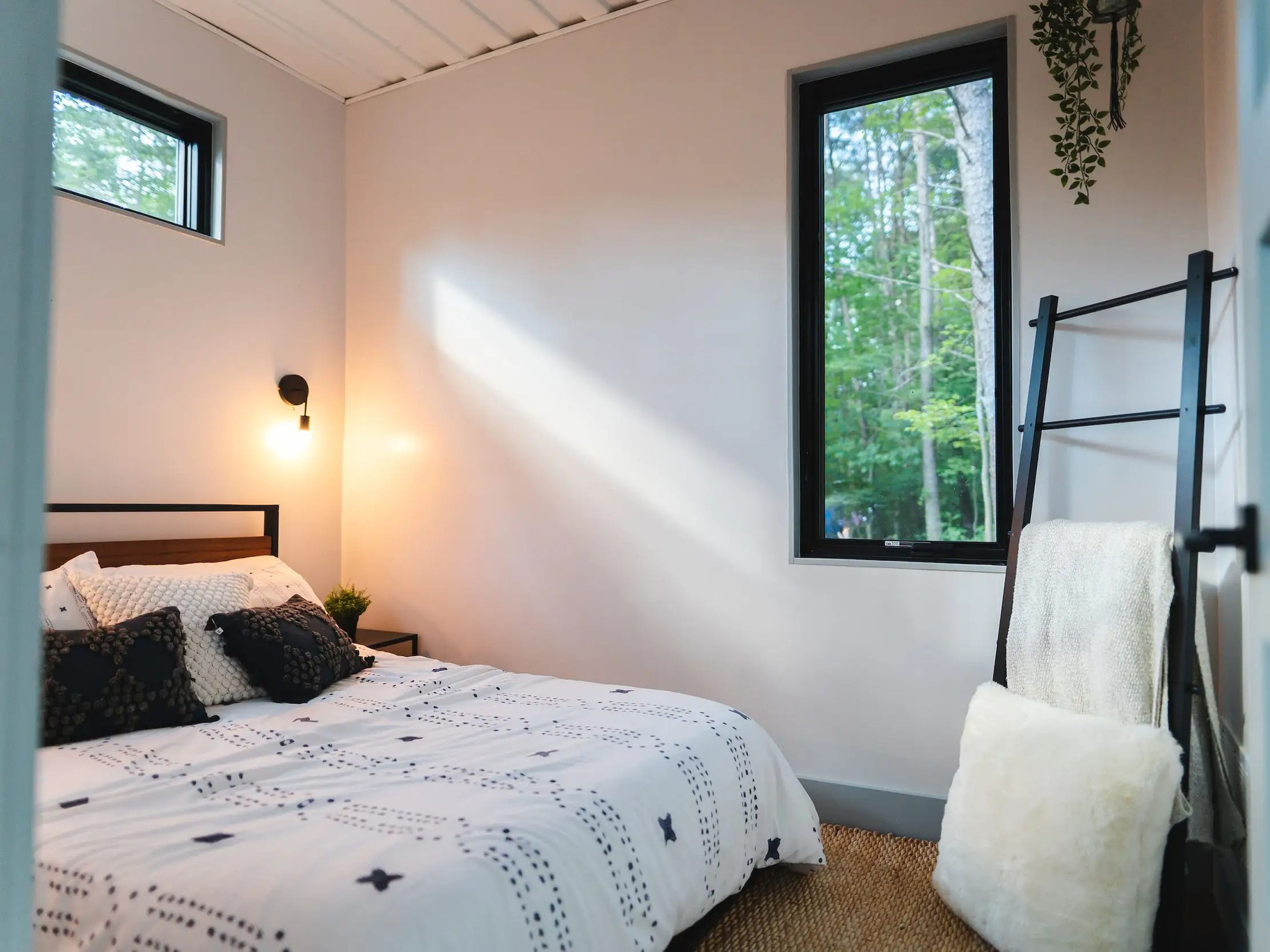 A bedroom with two windows and accents inside the OG Box, a shipping container home.