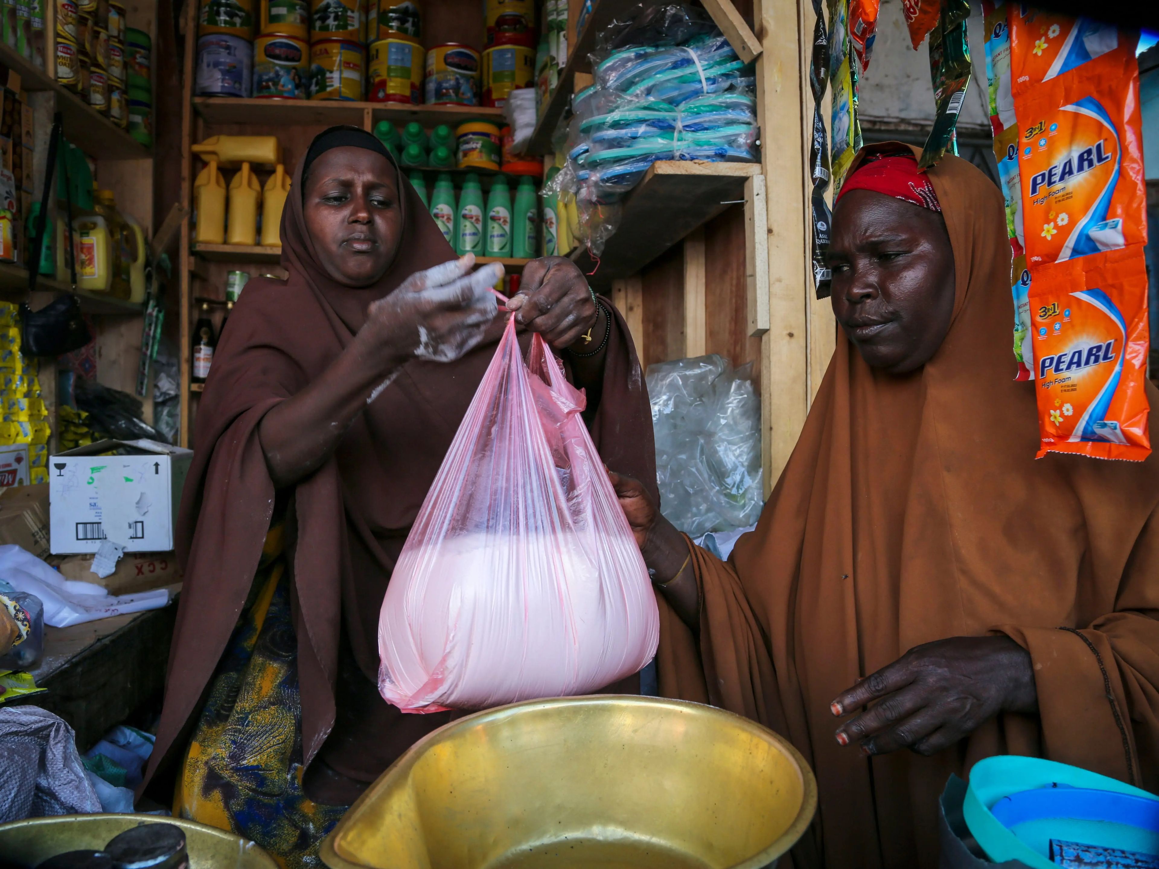 Halimo Hersi, de 42 años, a la derecha, compra harina de trigo a un comerciante en el mercado de Hamar-Weyne en la capital Mogadiscio, Somalia, el jueves 26 de mayo de 2022.
