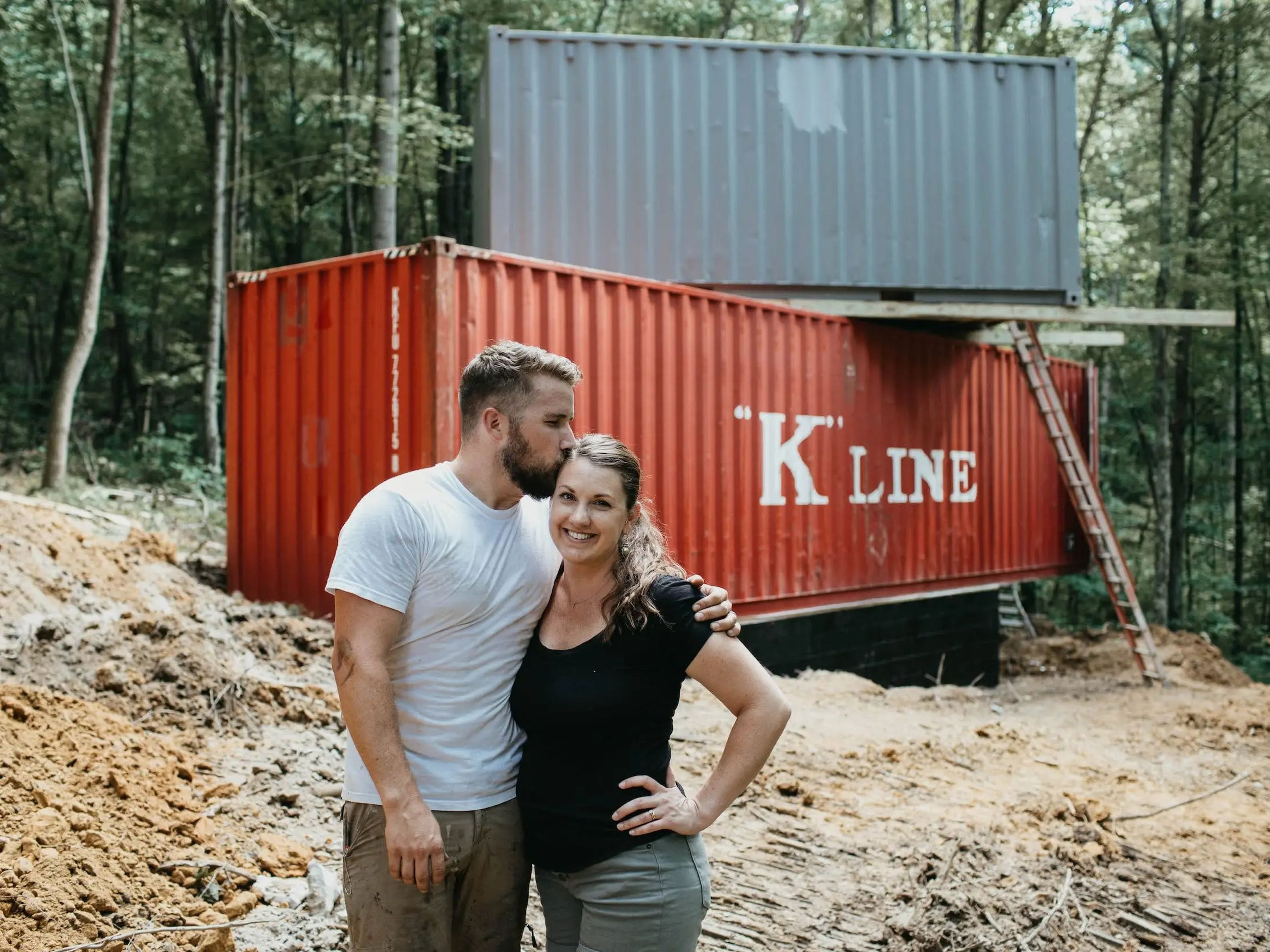 A couple standing in front of two stacked shipping containers.