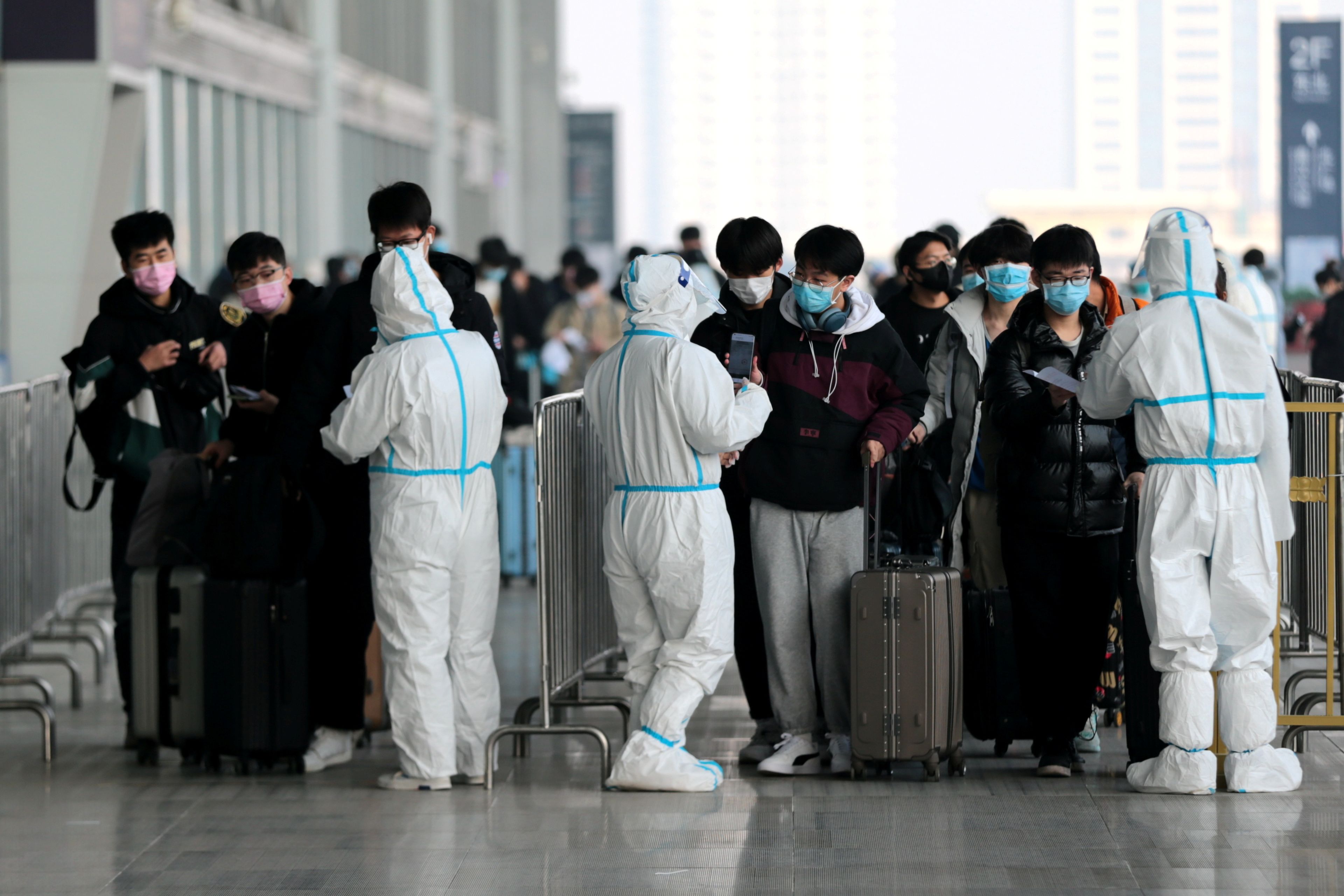 Estudiantes mostrando los resultados de sus pruebas de coronavirus a los trabajadores para entrar en la estación de tren de Xian Norte (China)