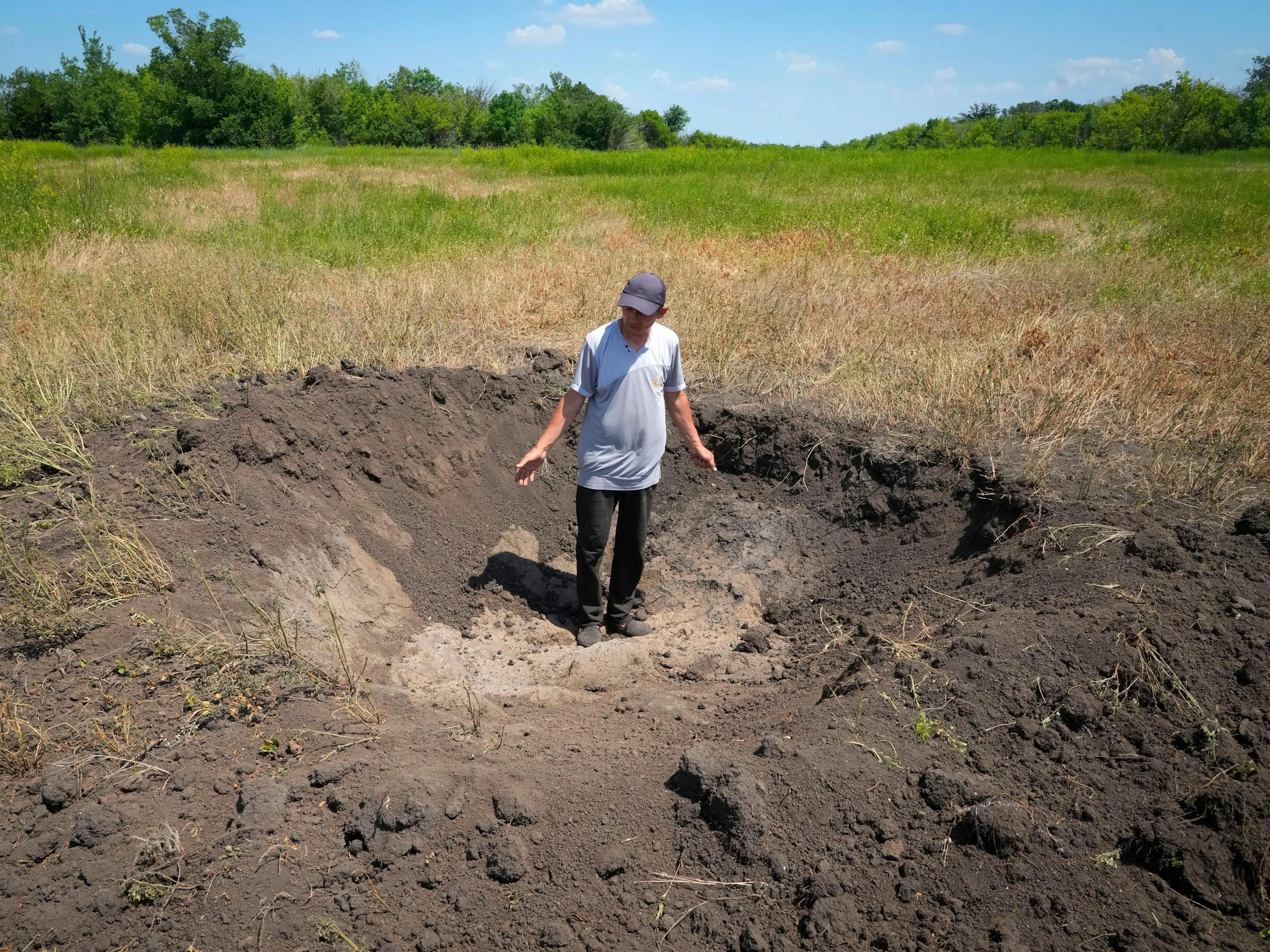 El agricultor Serhiy gesticula de pie cerca de un montón de grano en su granero en el pueblo de Ptyche en la región oriental de Donetsk, Ucrania, el domingo 12 de junio de 2022.