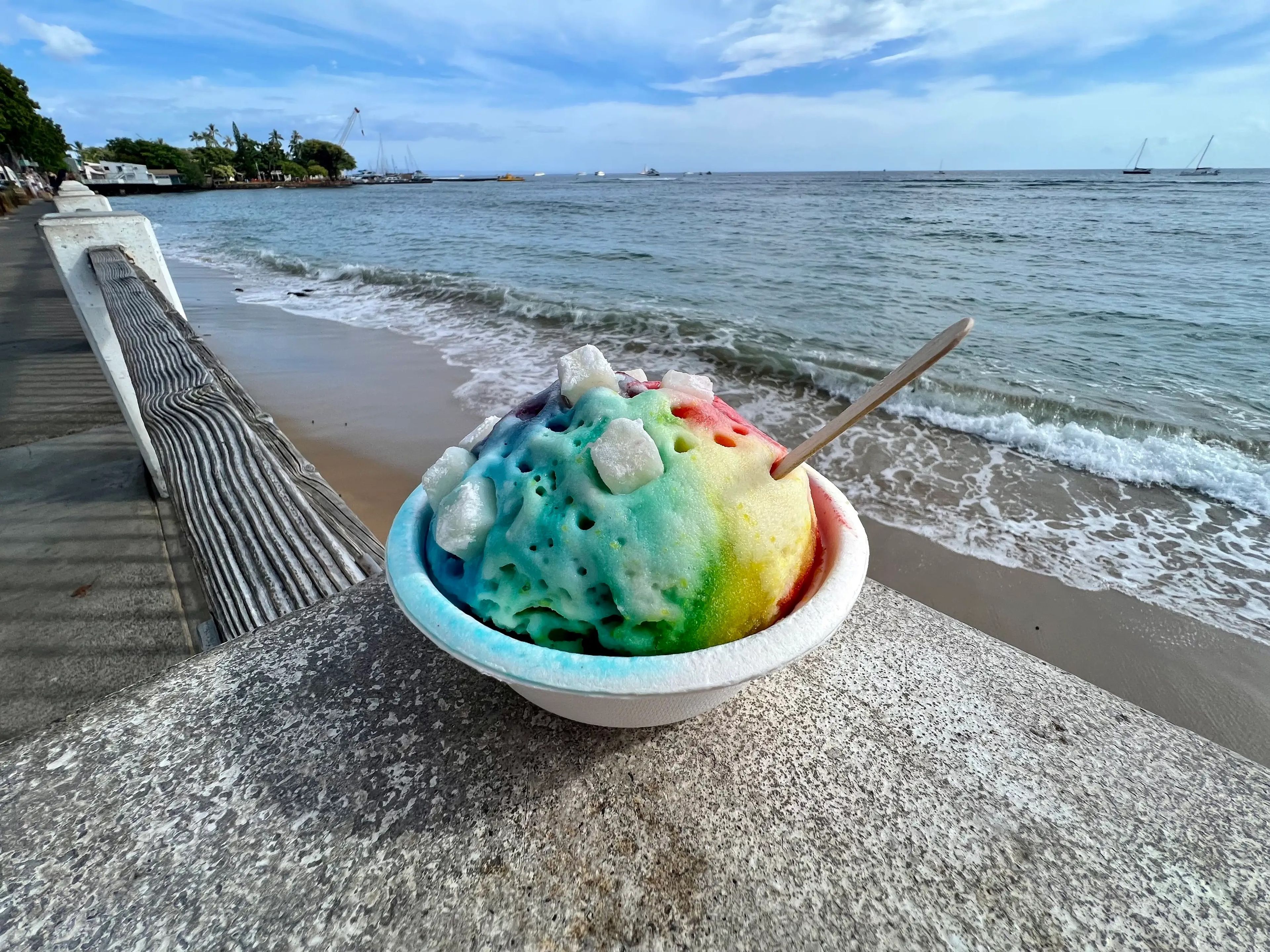 hawaiian shave ice, rainbow treat with water in the background