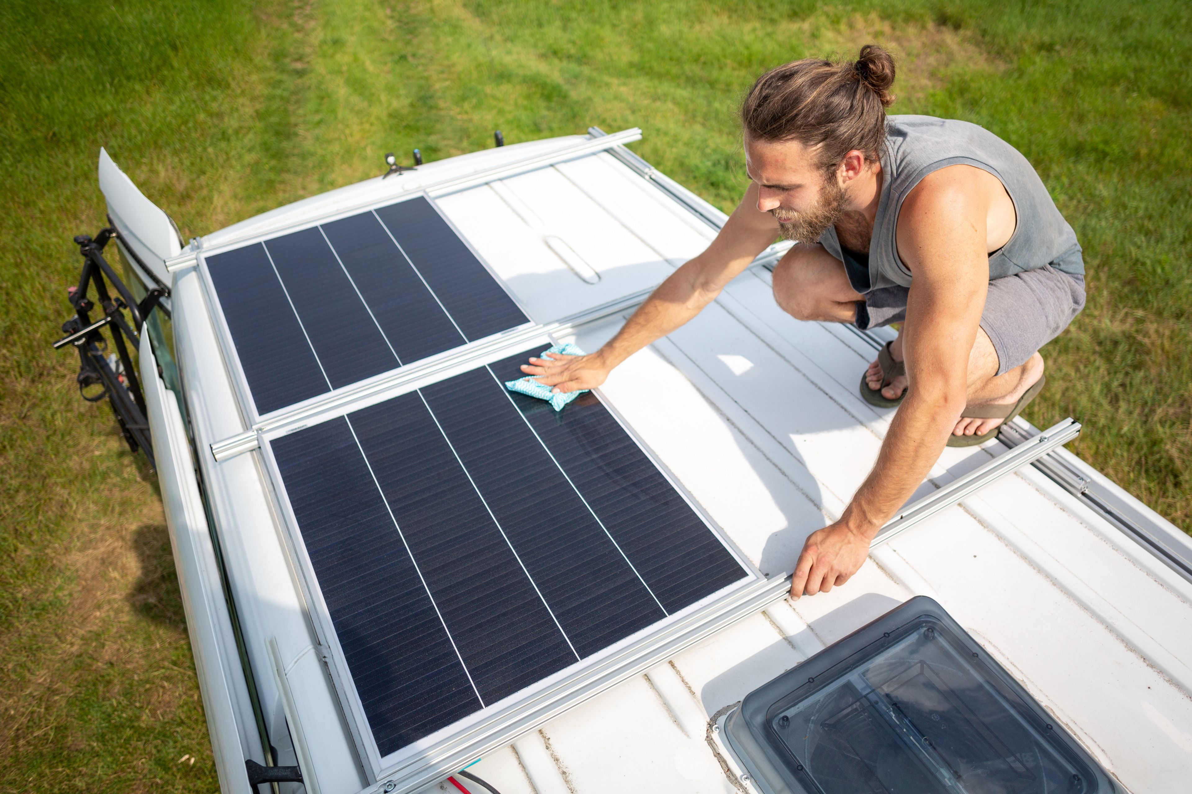 Un hombre coloca unos paneles solares en el techo de una furgoneta.