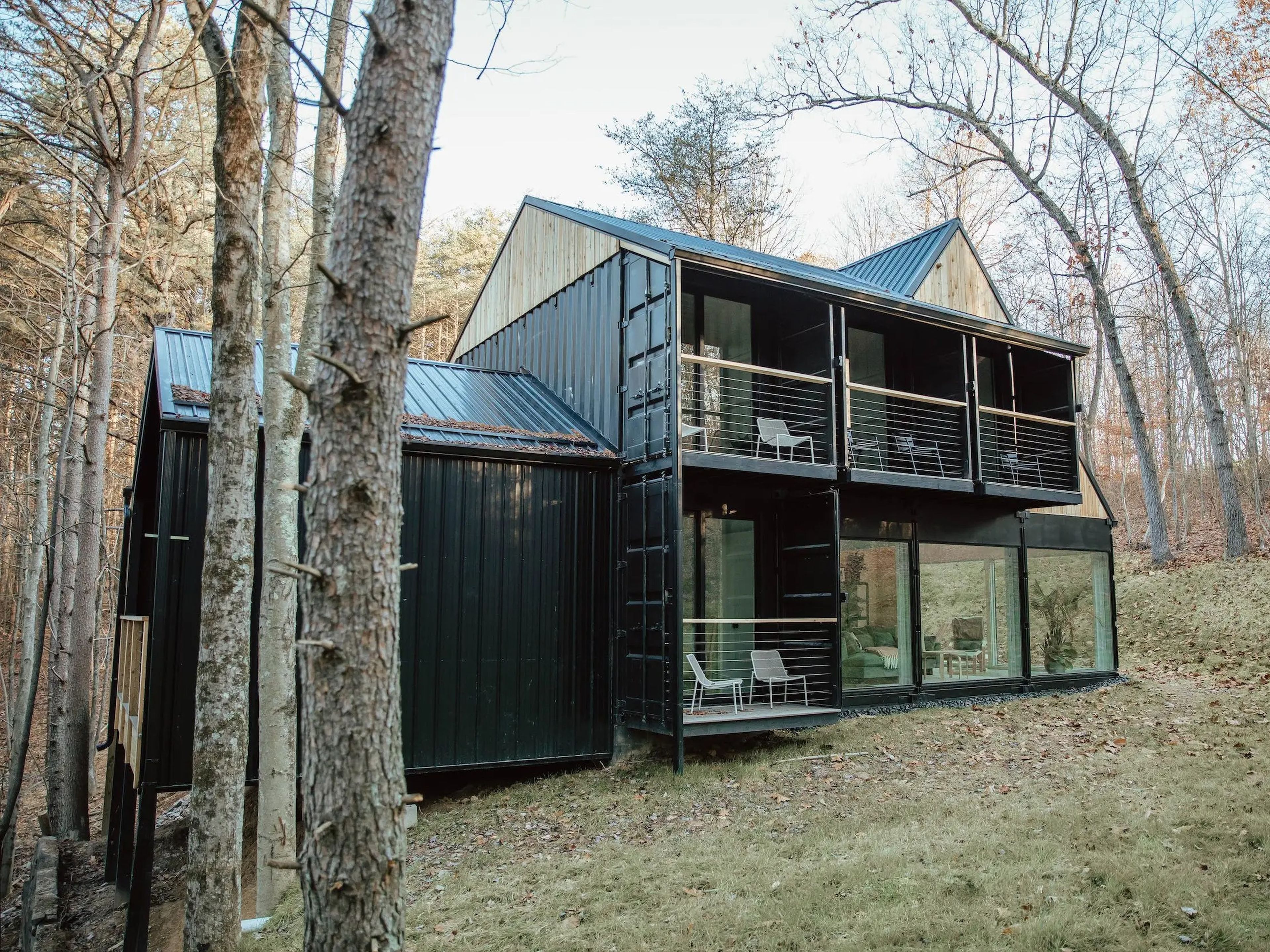 Hygge, a shipping container home, surrounded by trees.