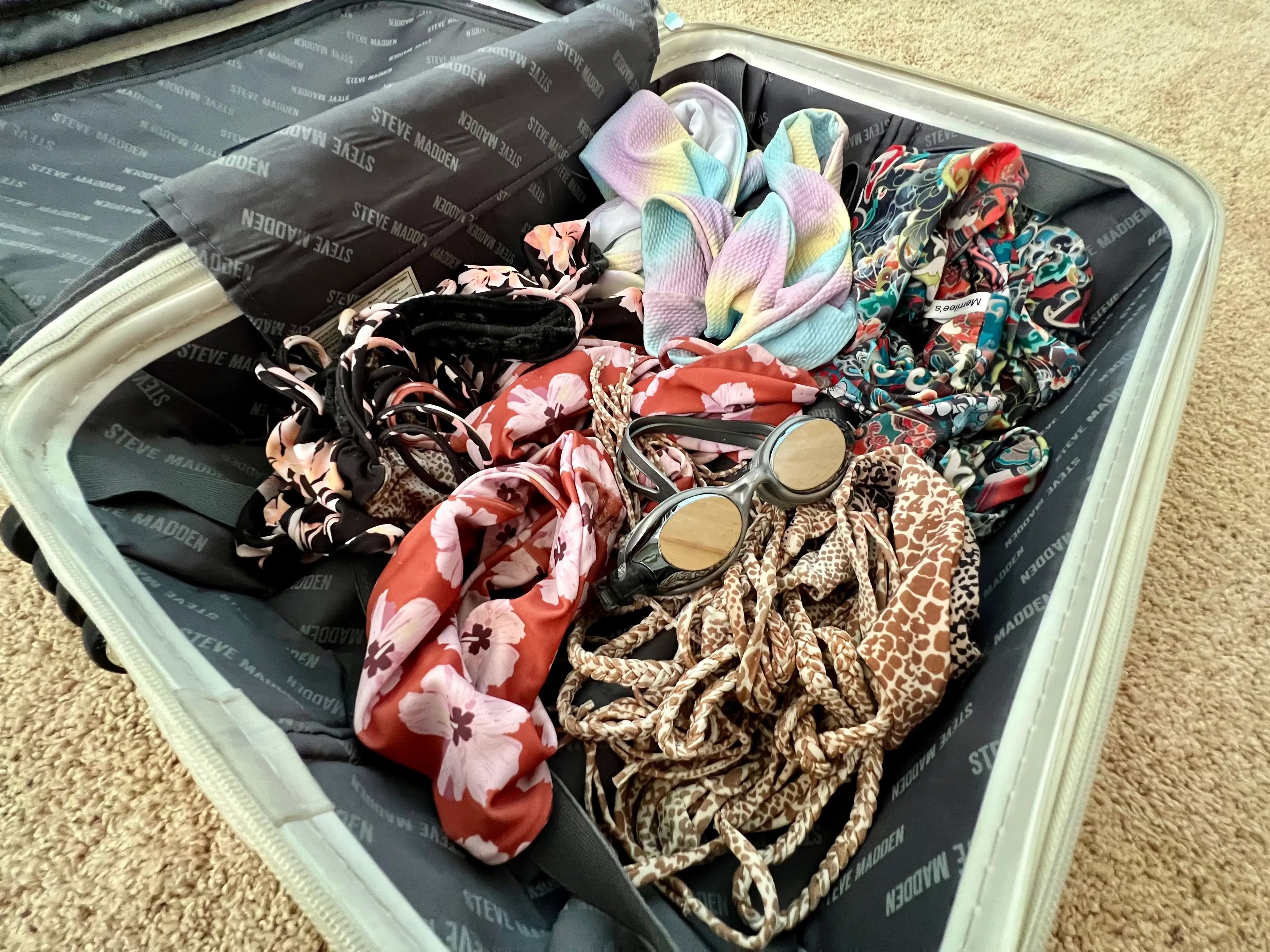 inside of suitcases with goggles, swimsuit, and beach clothes