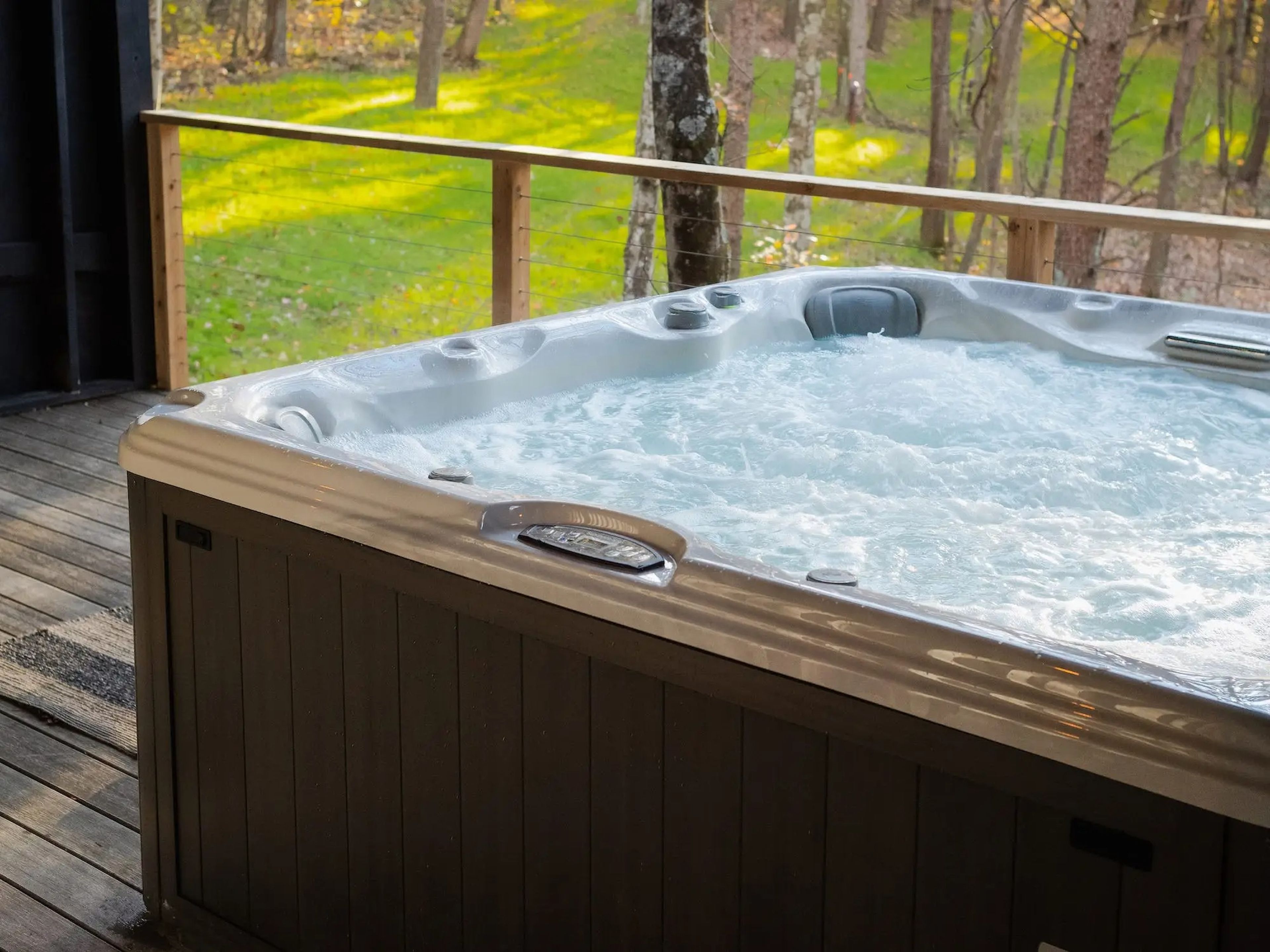 A jacuzzi on a deck overlooking trees inside Hygge, a shipping container home.