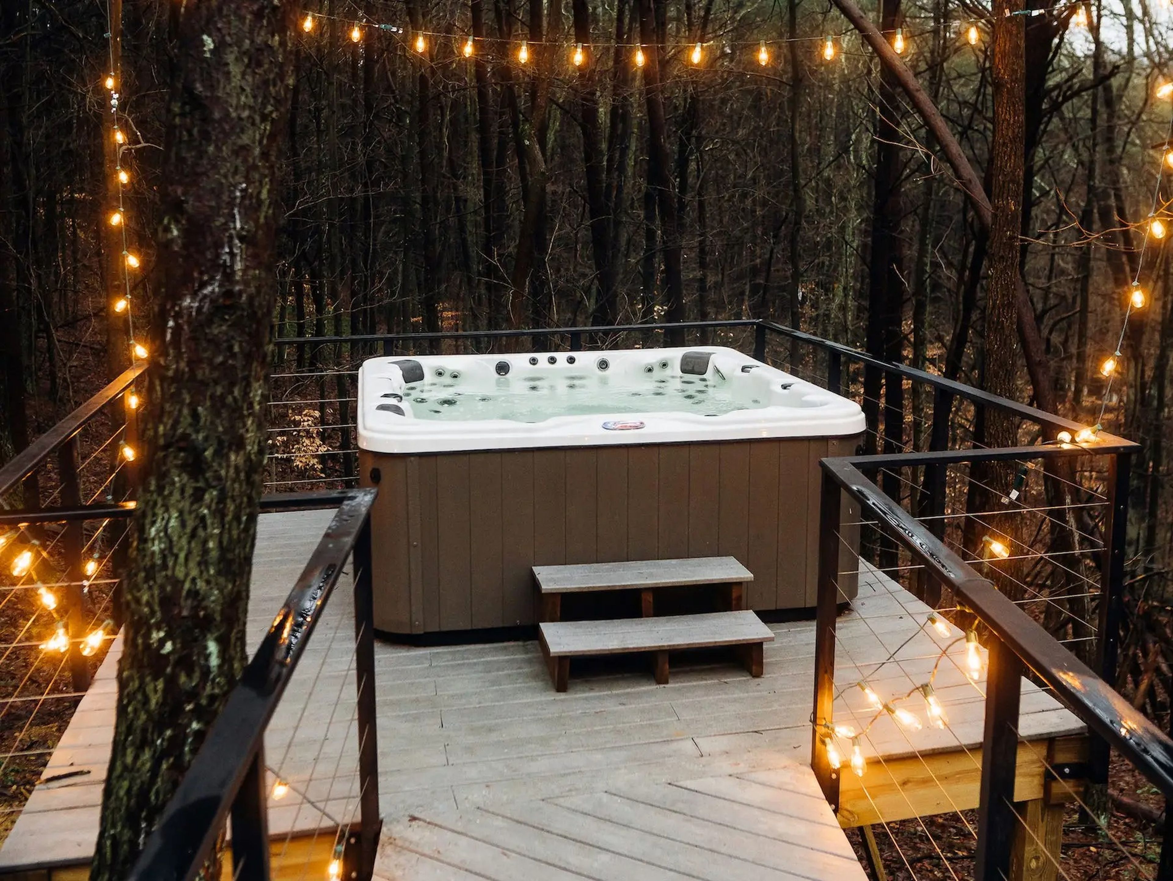 A Jacuzzi on a deck surrounded by string lights
