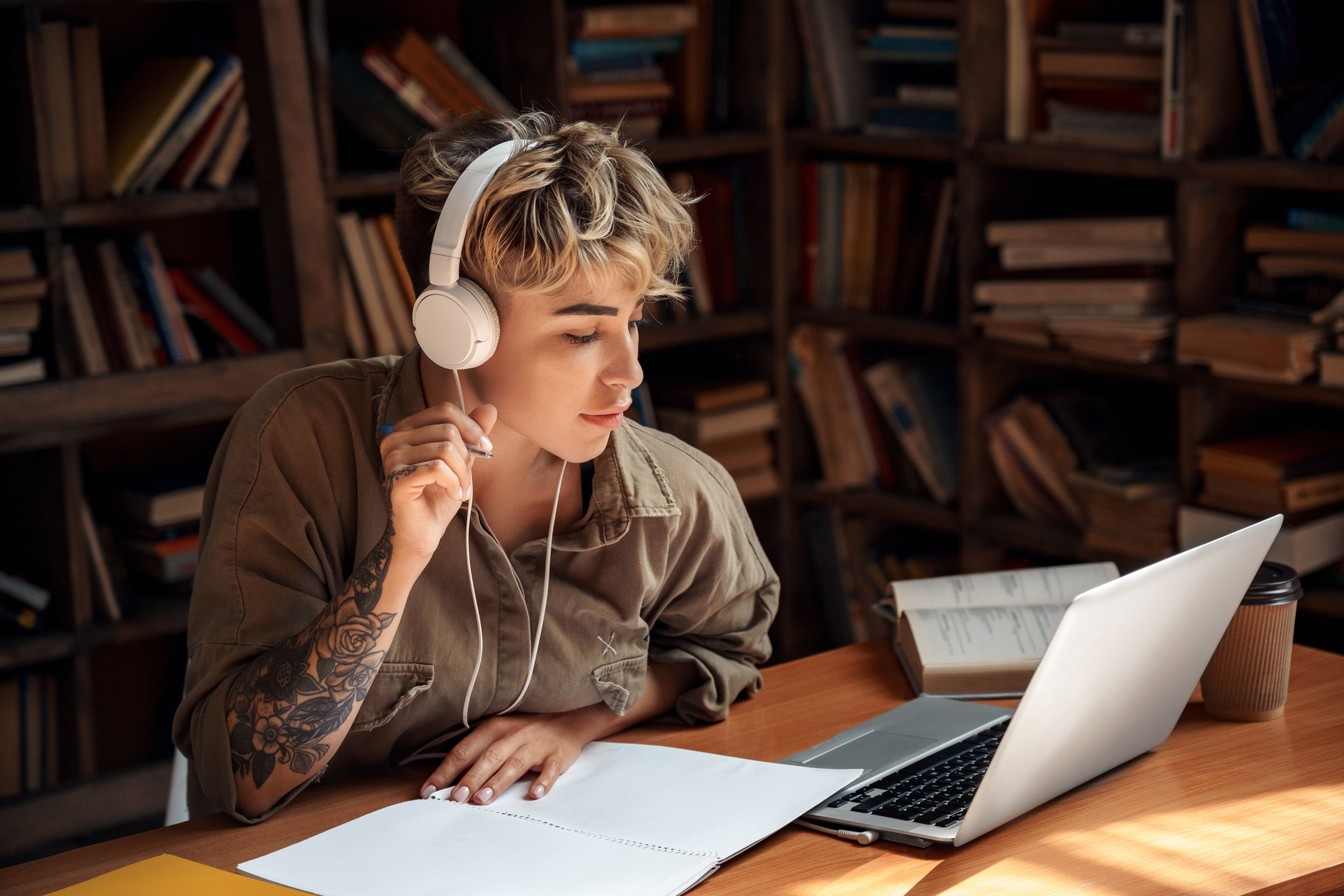 Una joven estudia, mientras escucha música con unos auriculares.