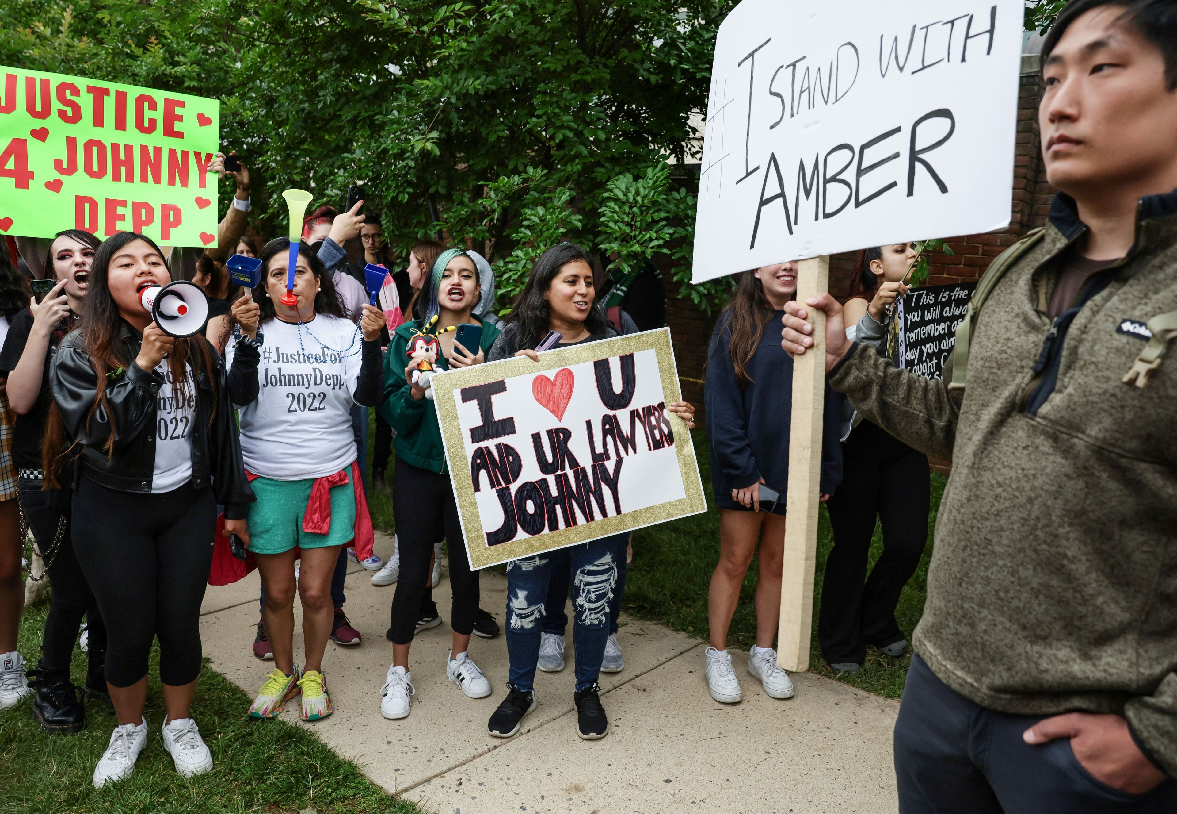 Un manifestante sostiene un cartel de apoyo a Amber Heard en medio de una multitud de fans de Johnny Depp, a las afueras del Tribunal de Fairfax, Virginia.