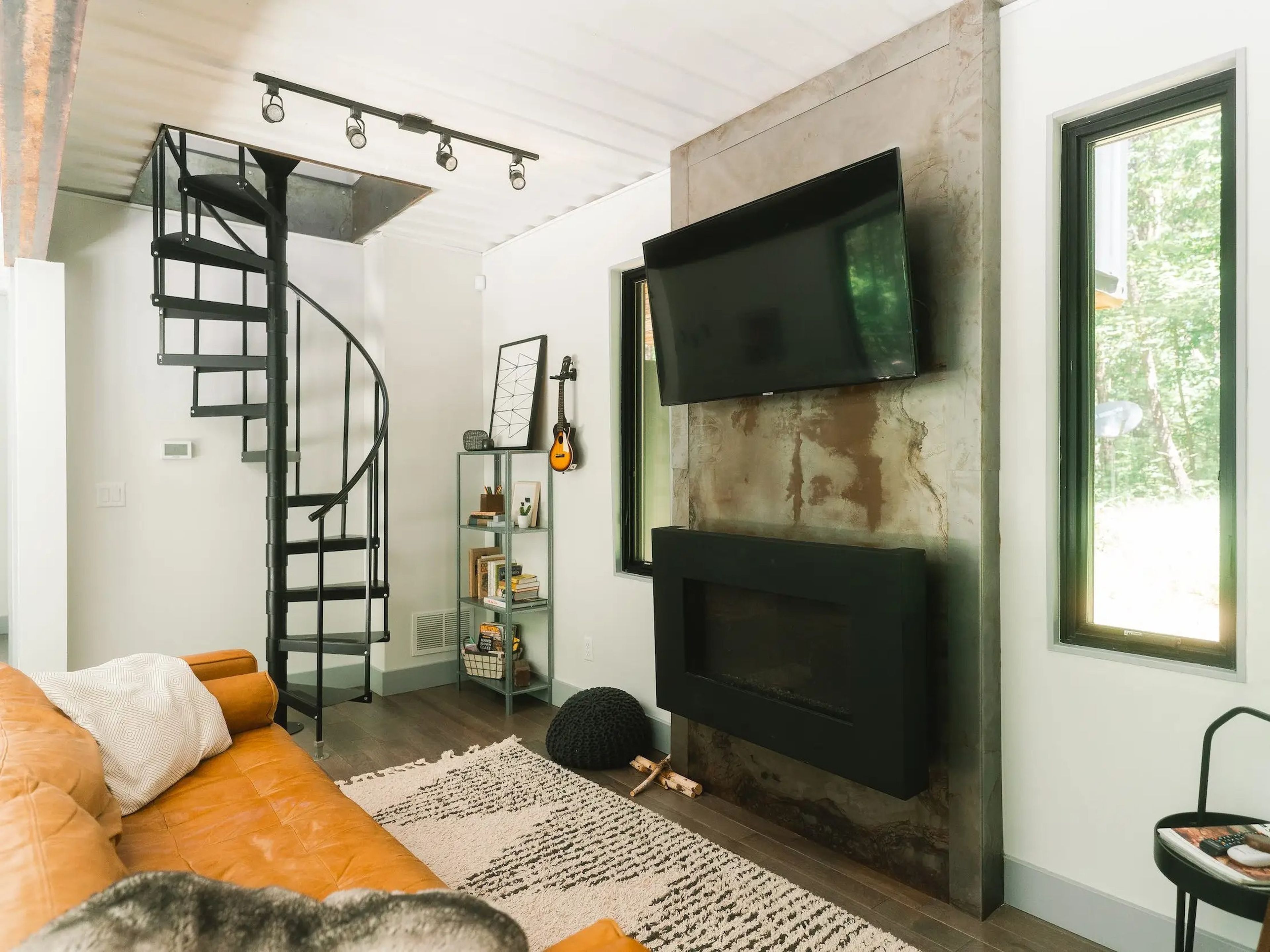 The living room with a couch, TV, fireplace inside the OG Box, a shipping container home.