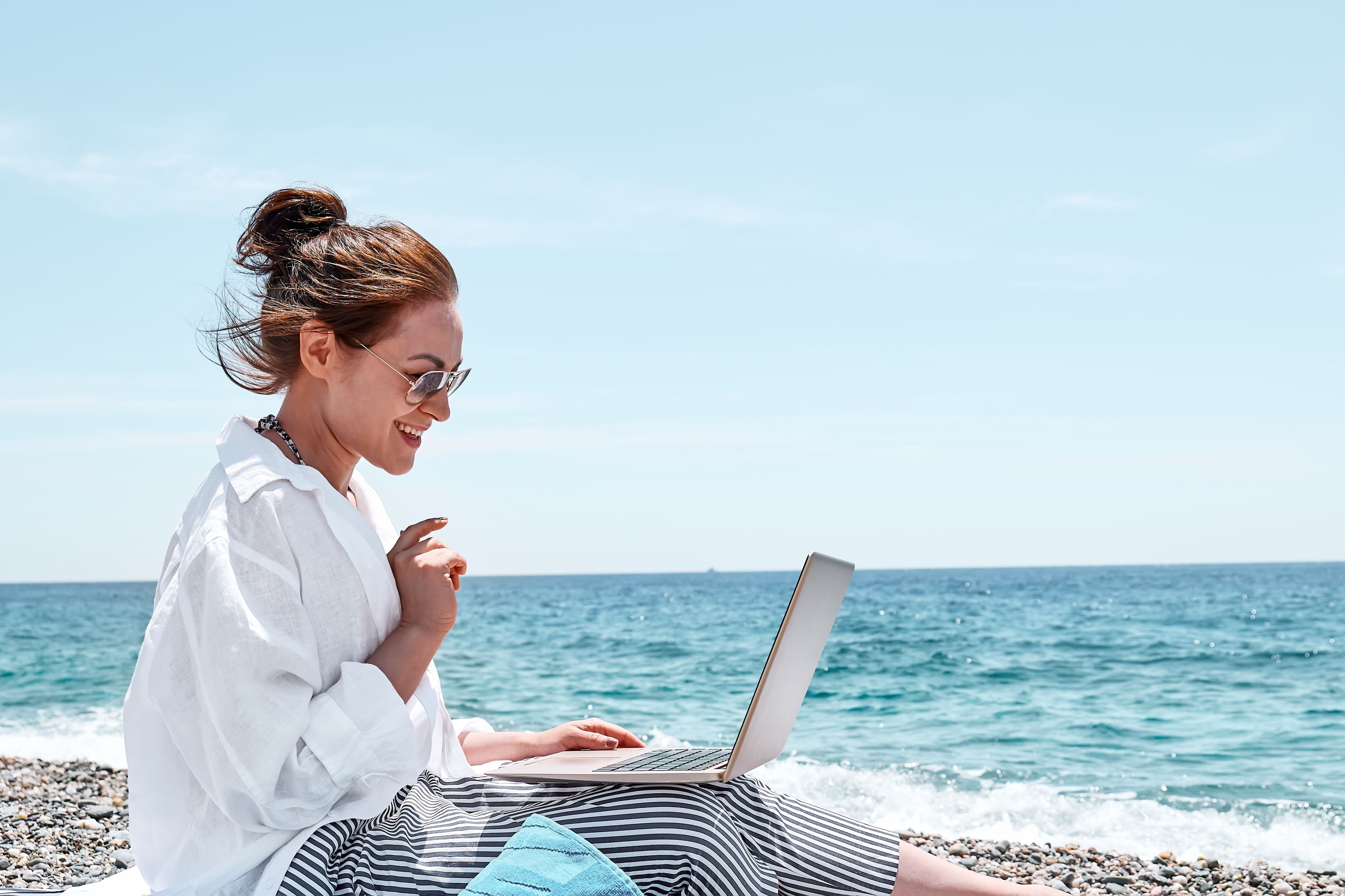 Una mujer joven con el ordenador en la playa