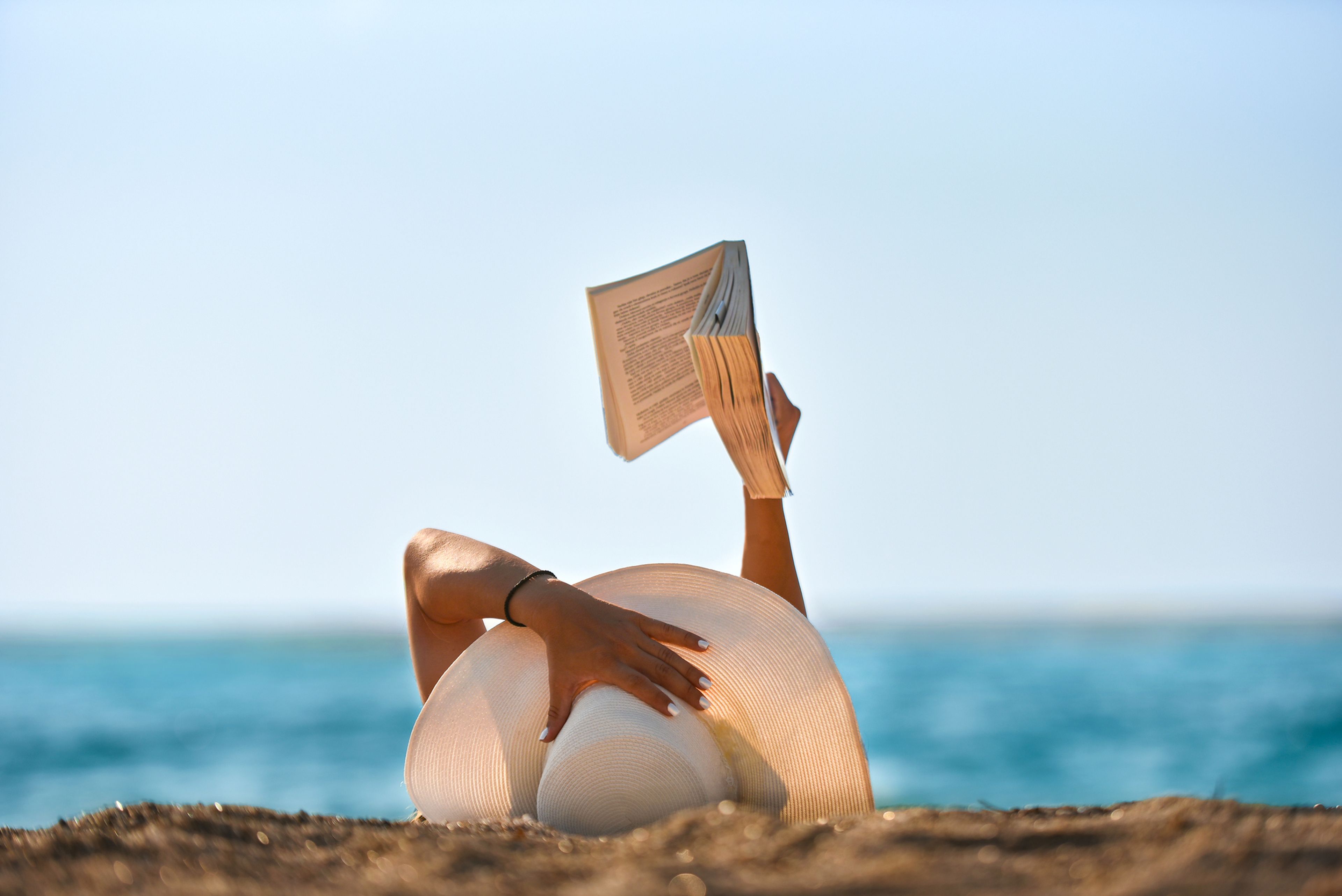 Una mujer lee un libro en la playa en verano