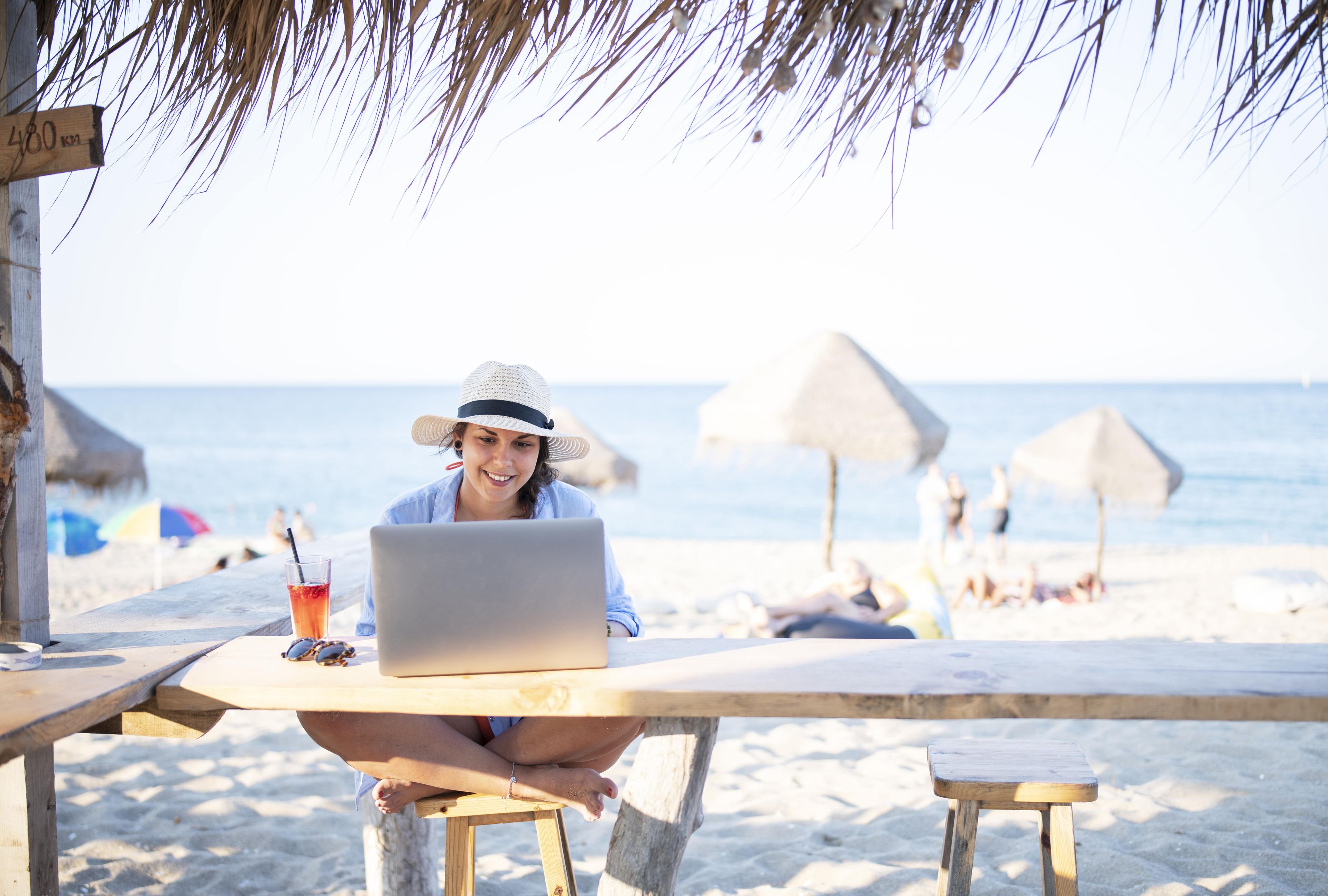 Una mujer trabajando con el portátil en la playa