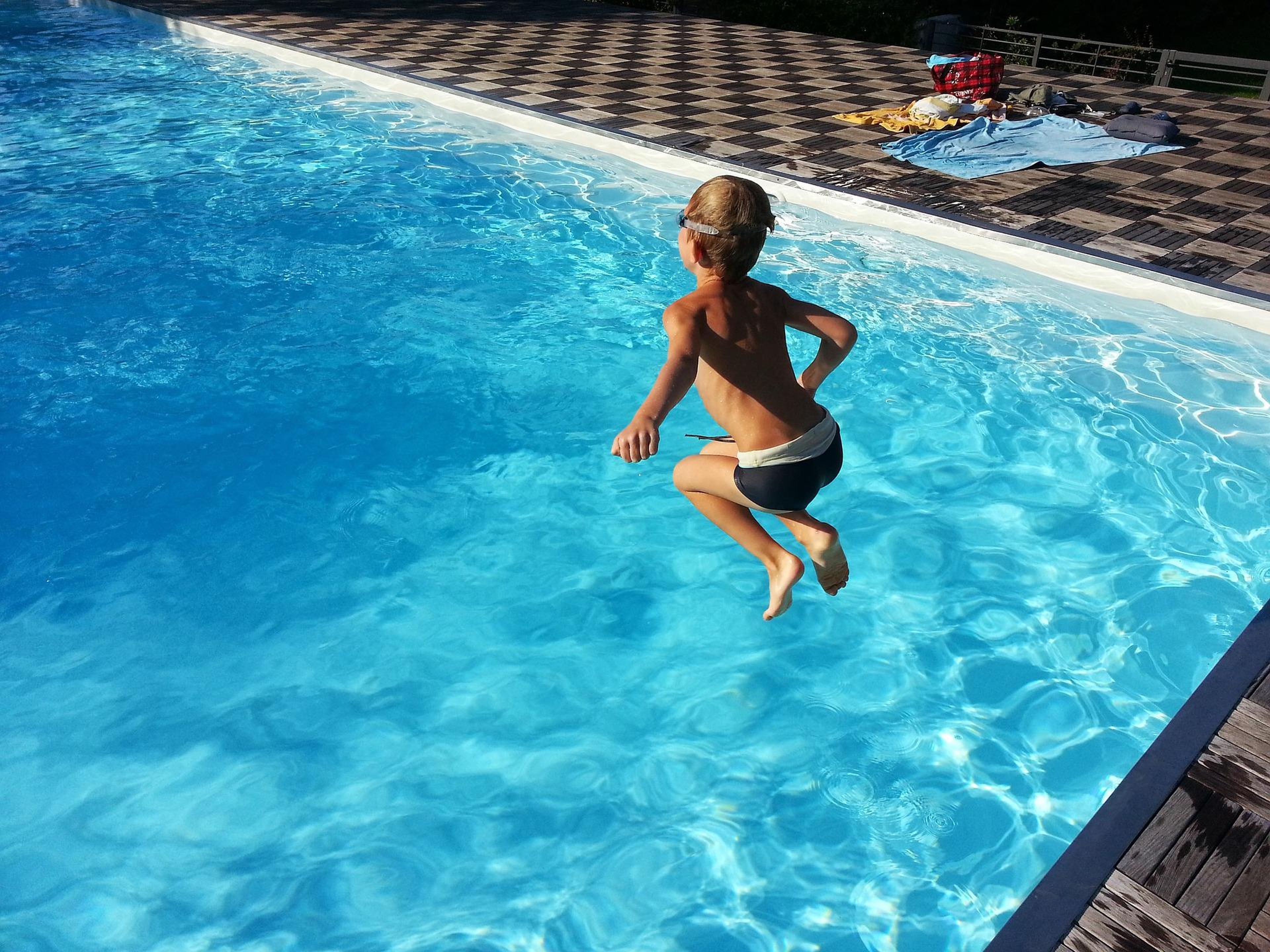 Un niño se tira a la piscina.