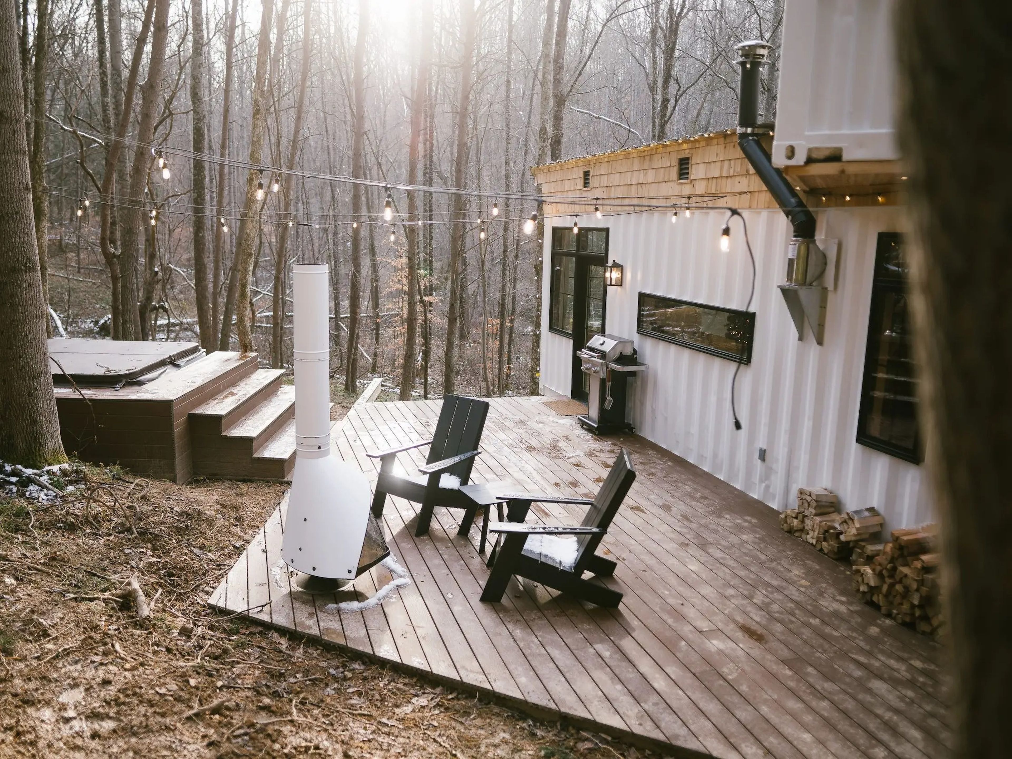 An outdoor deck with chairs and a fireplace at a shipping container home.