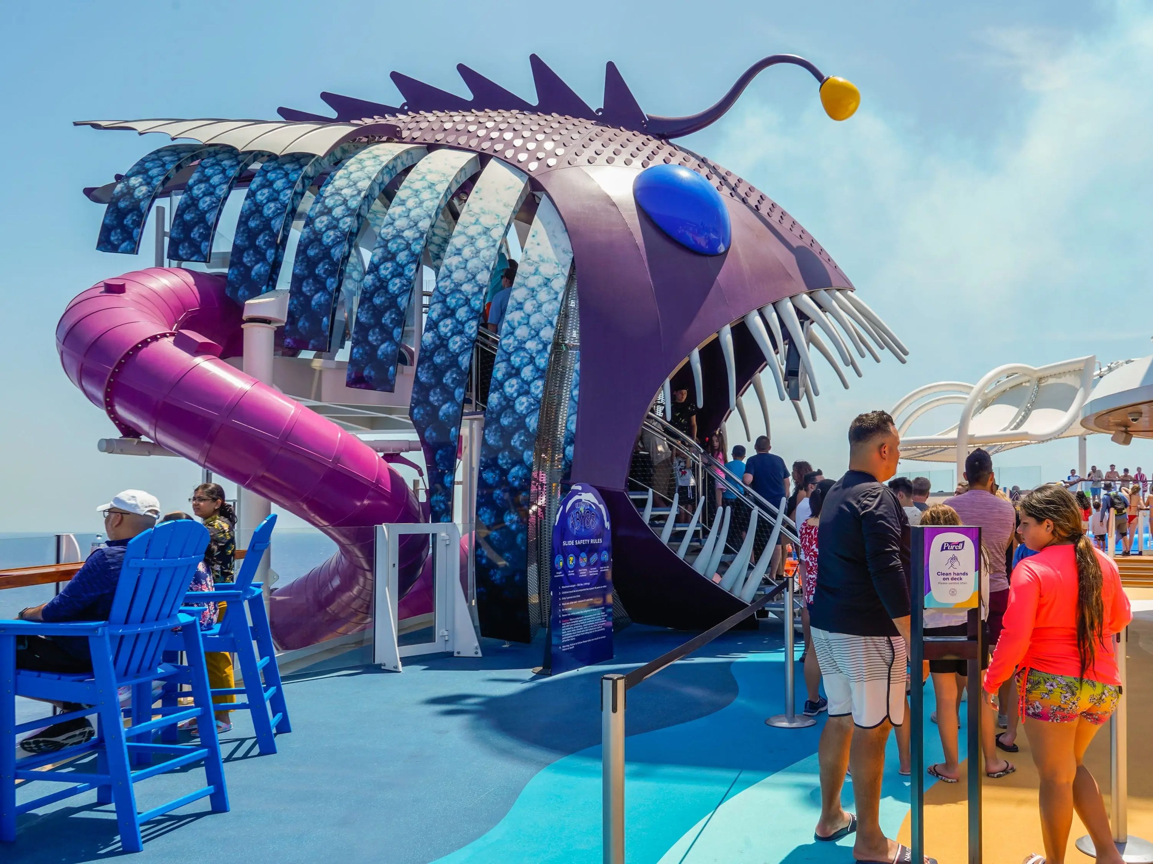 People wait in line to go down a big slide in the shape of a sharp-toothed fish onboard Wonder of the Seas