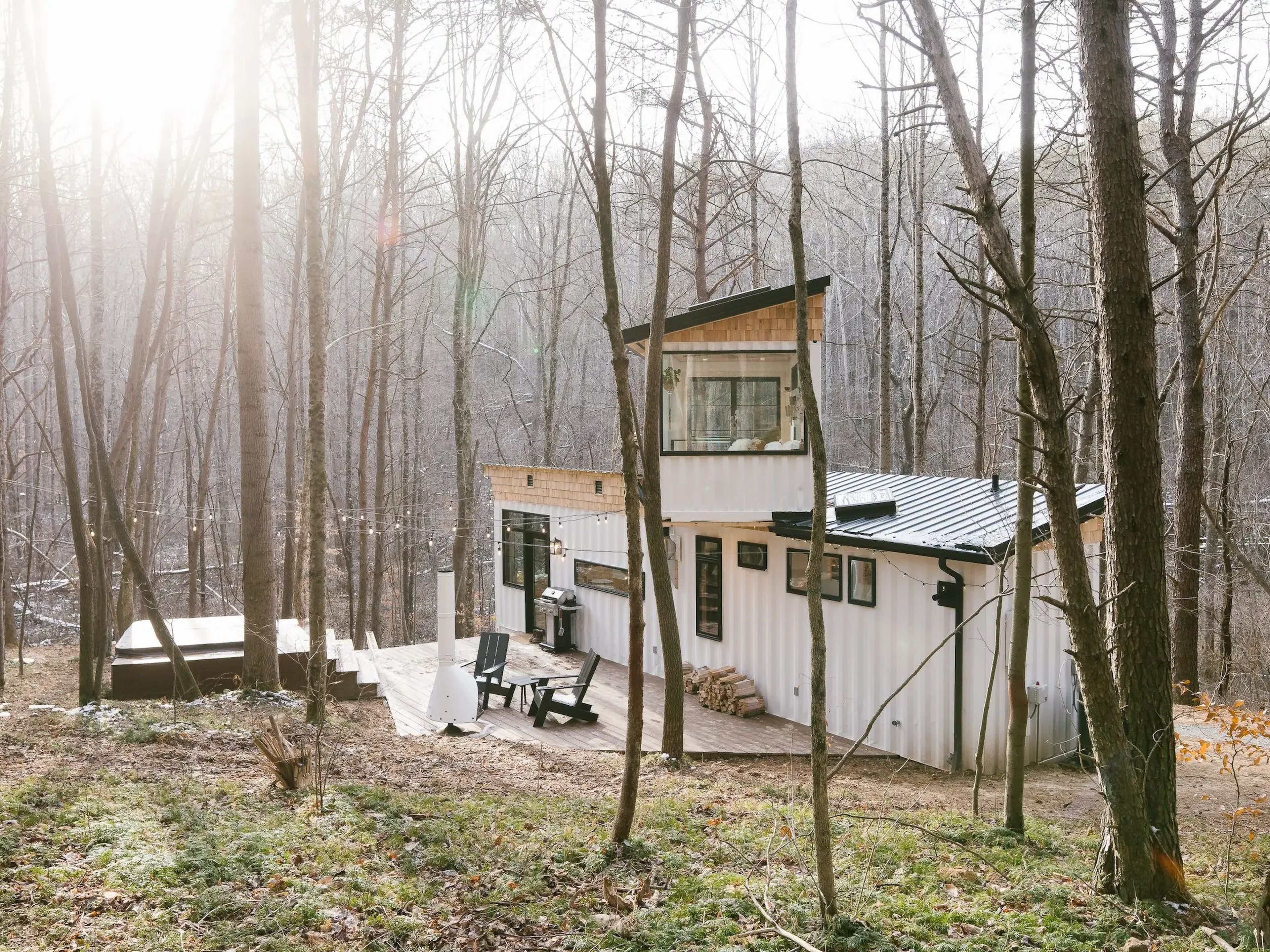 A shipping container home surrounded by trees and grass.