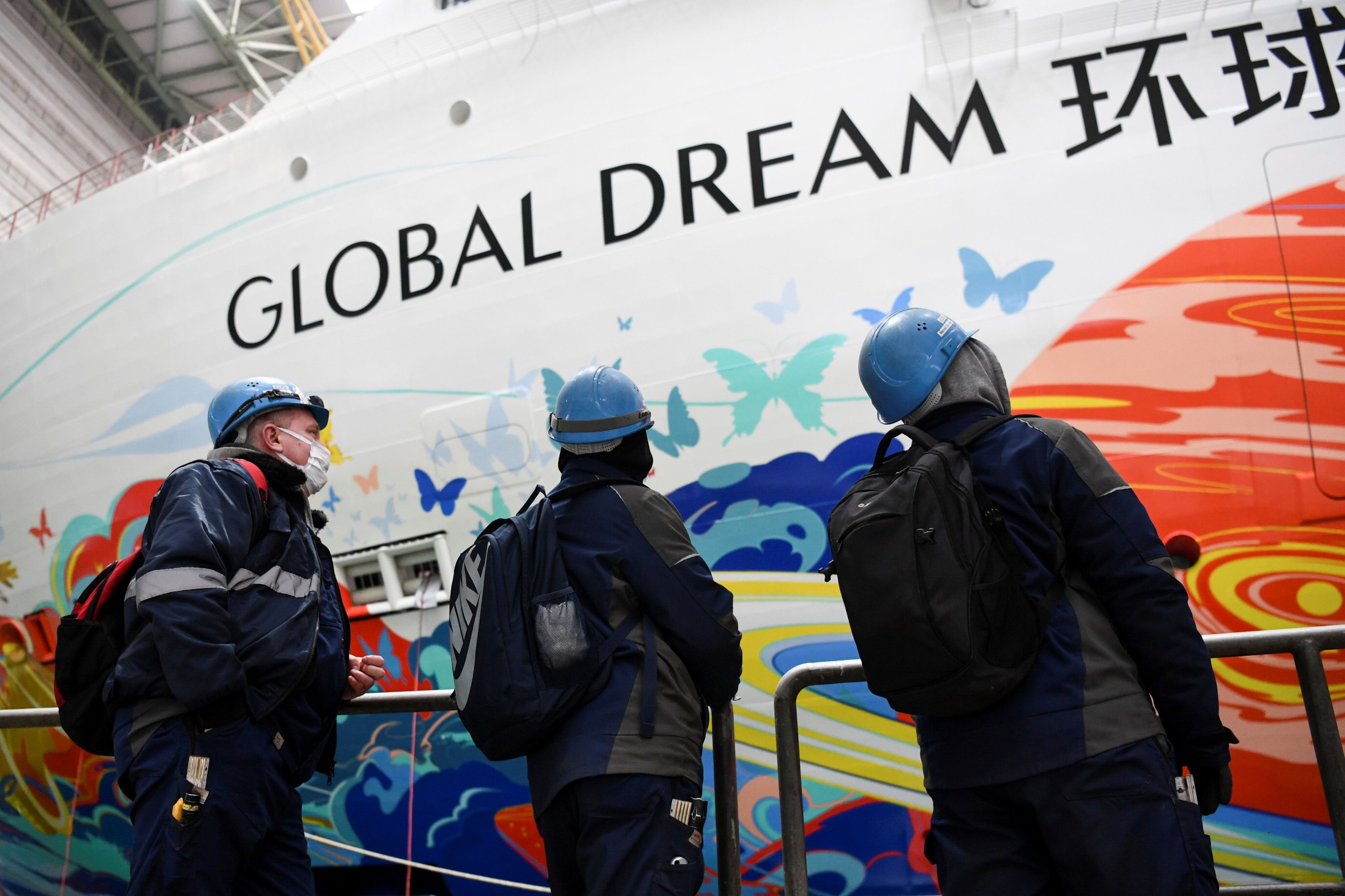 Trabajadores junto al crucero Global Dream de los astilleros MV Werften.