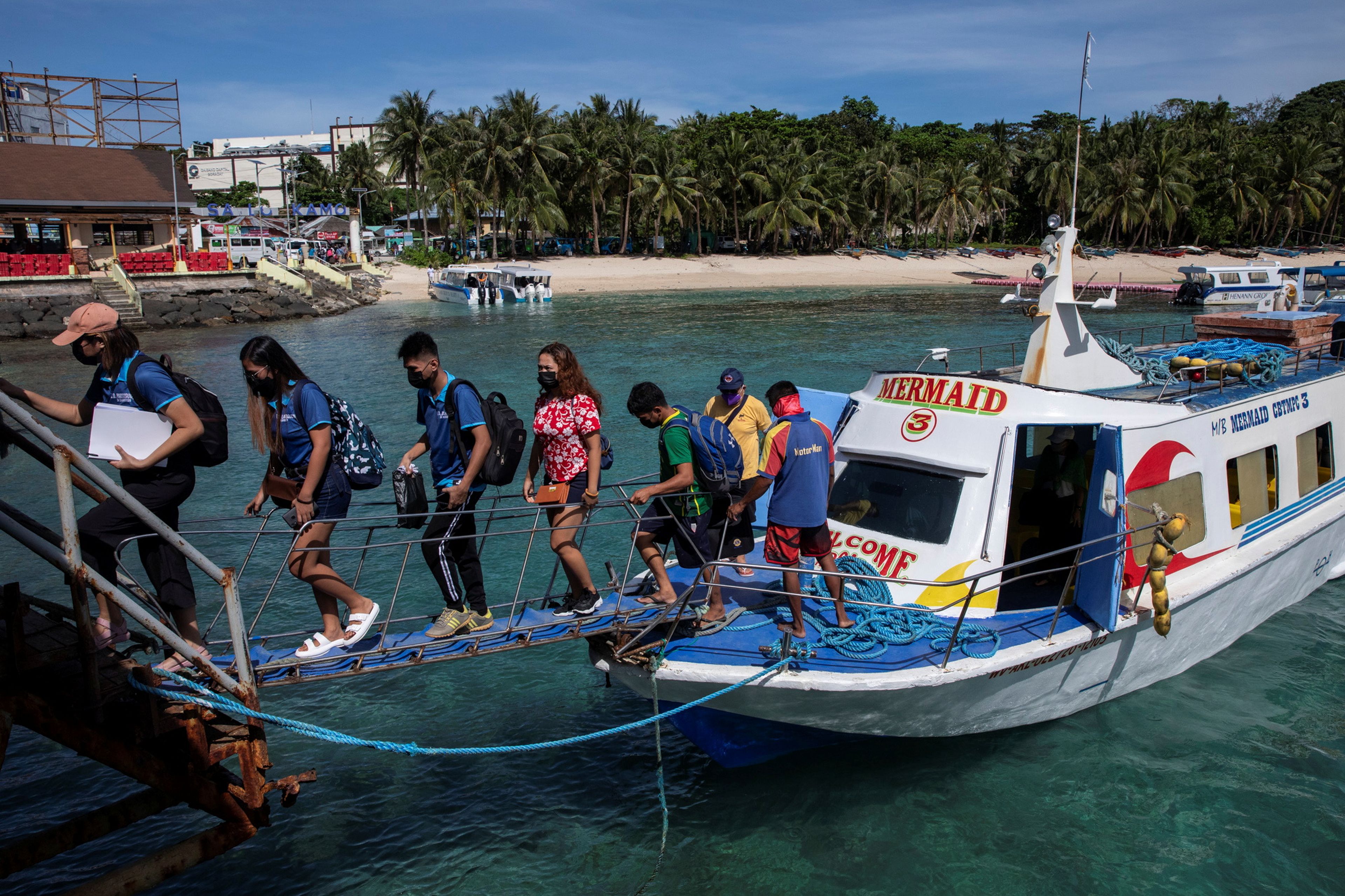 Turistas en Filipinas bajan de un barco junto a la playa
