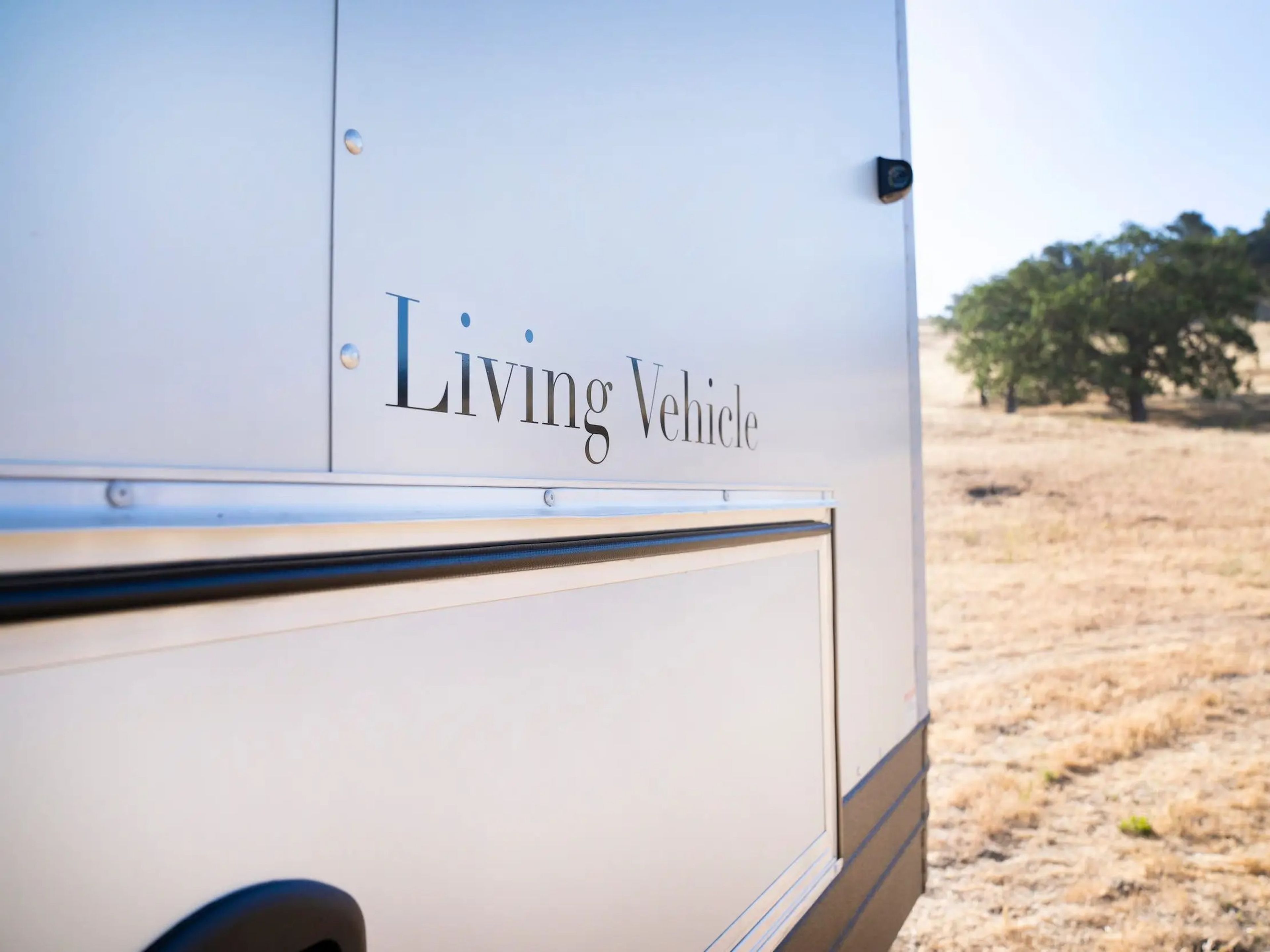 A close up of the exterior of the travel trailer with Living Vehicle's logo.