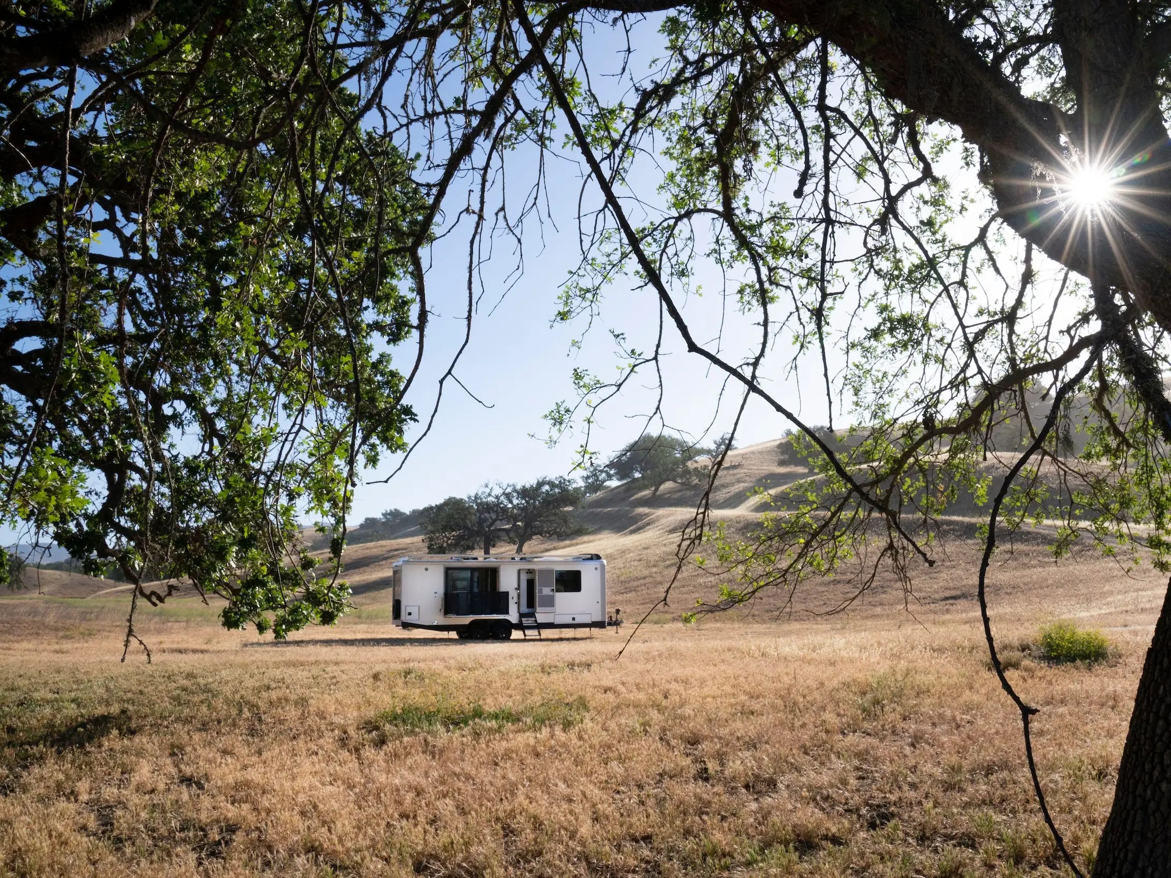The exterior of the travel trailer as it sits on a brown field.