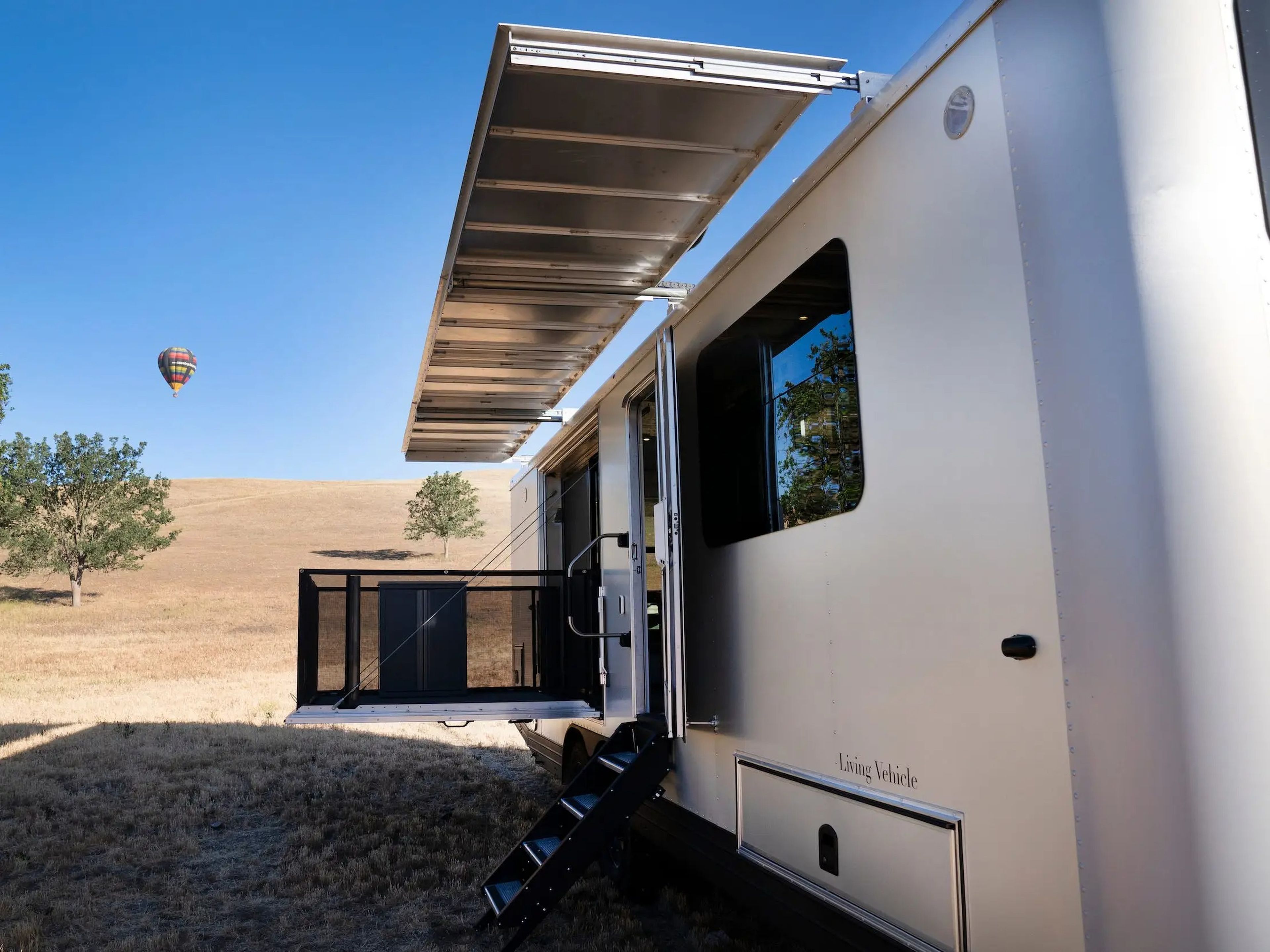 The exterior of the travel trailer as it sits on a brown field. The awning and patio are extended.