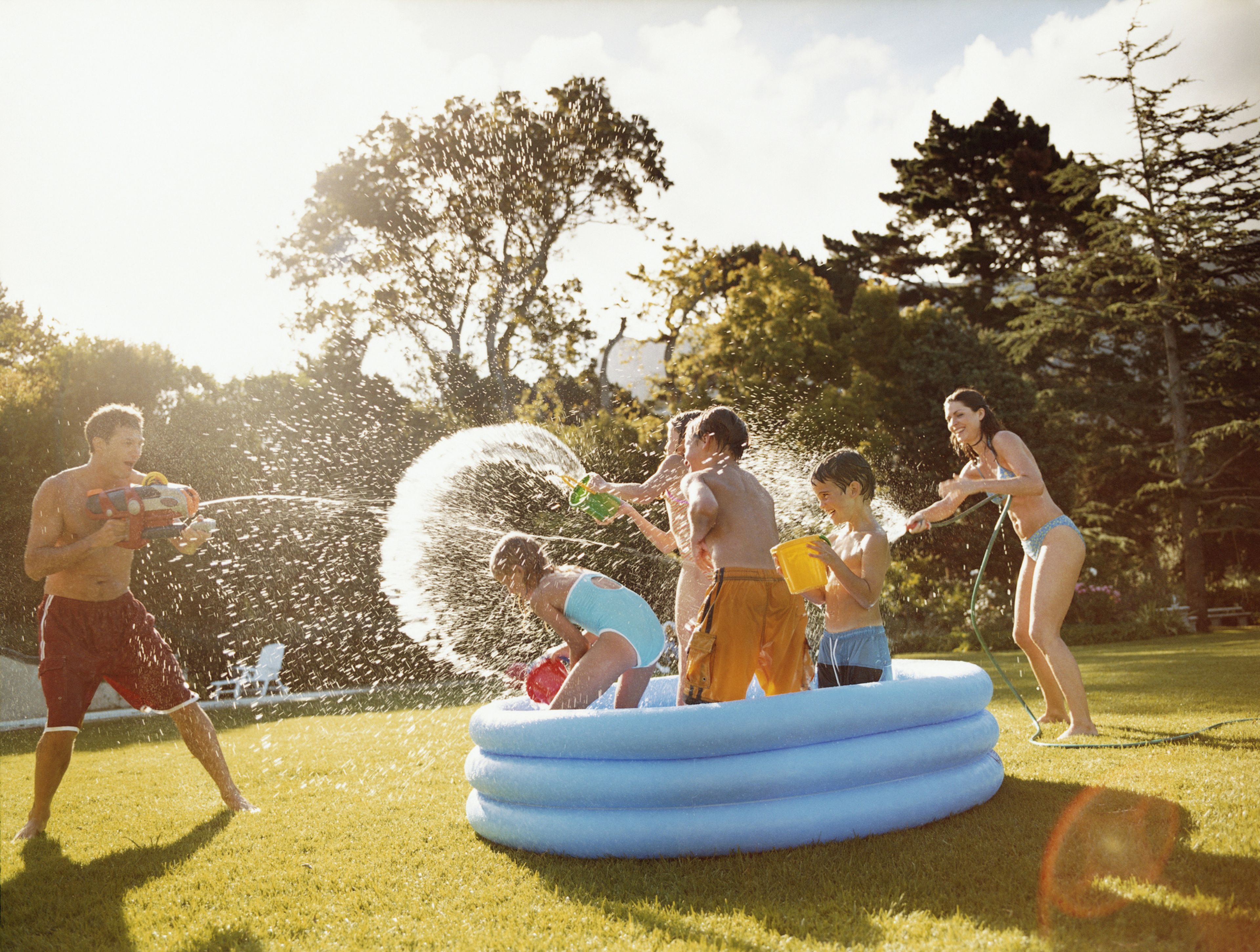Una familia juega con agua, con una piscina y una pistola de agua