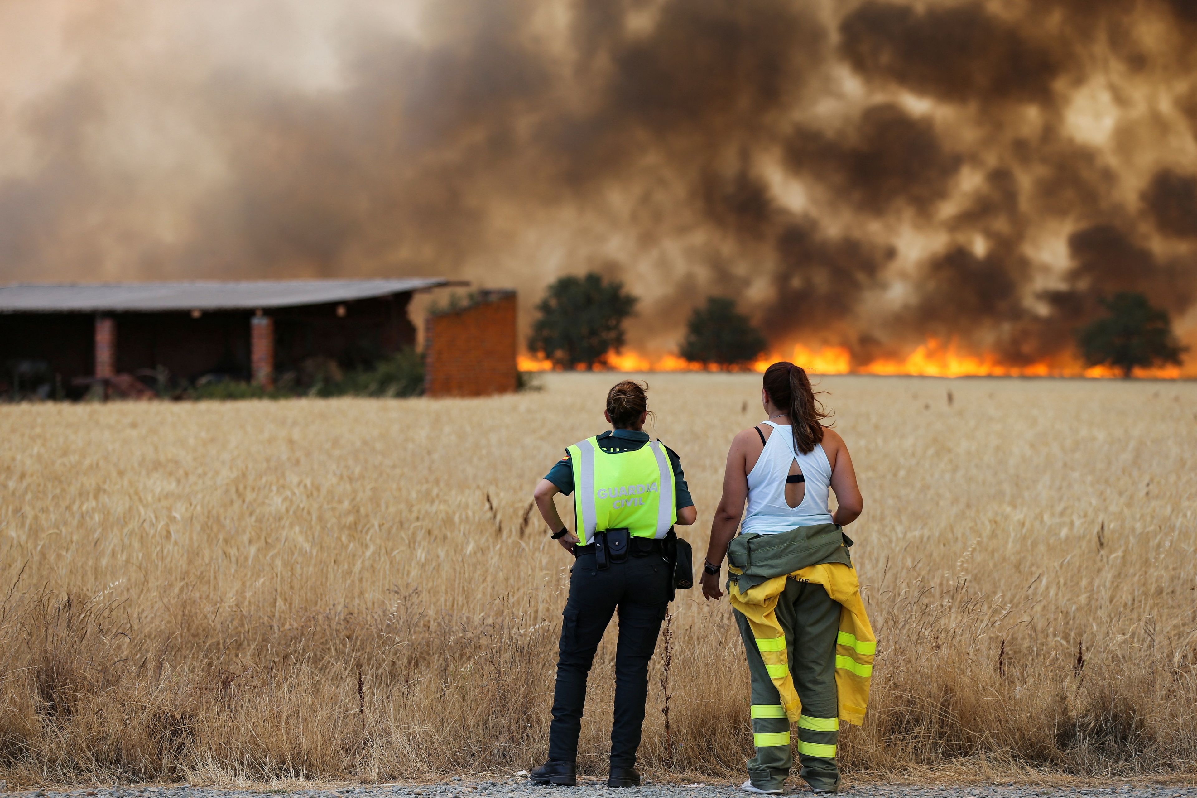 Una guardia civil y una bombera de las Brigadas de Refuerzo en Incendios Forestales (BRIF) observan cómo el fuego llega cerca de Tábara, Zamora, donde se han quemado más de 10.000 hectáreas, en la segunda ola de calor de 2022.