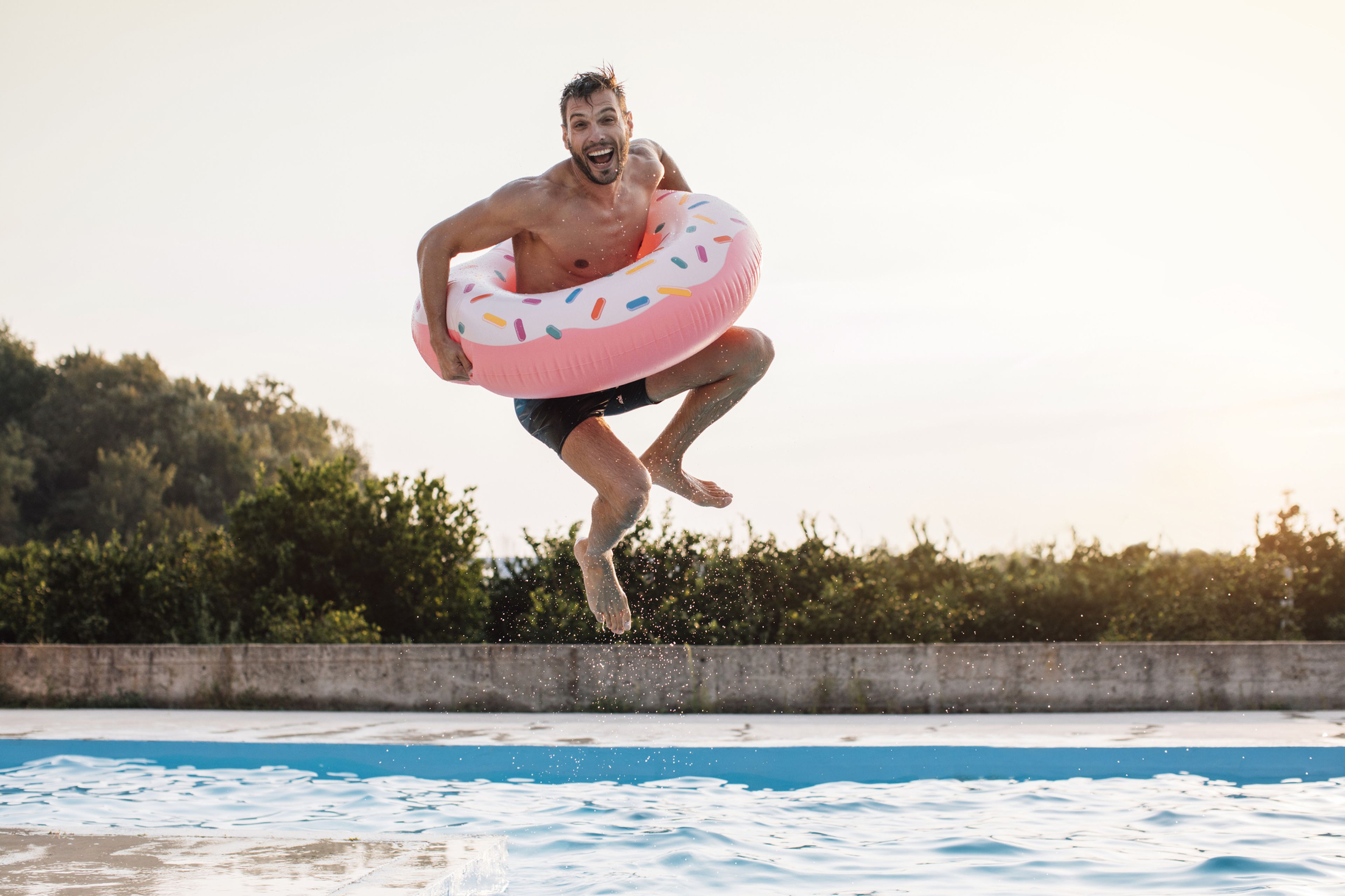 Hombre saltando a una piscina con un flotador