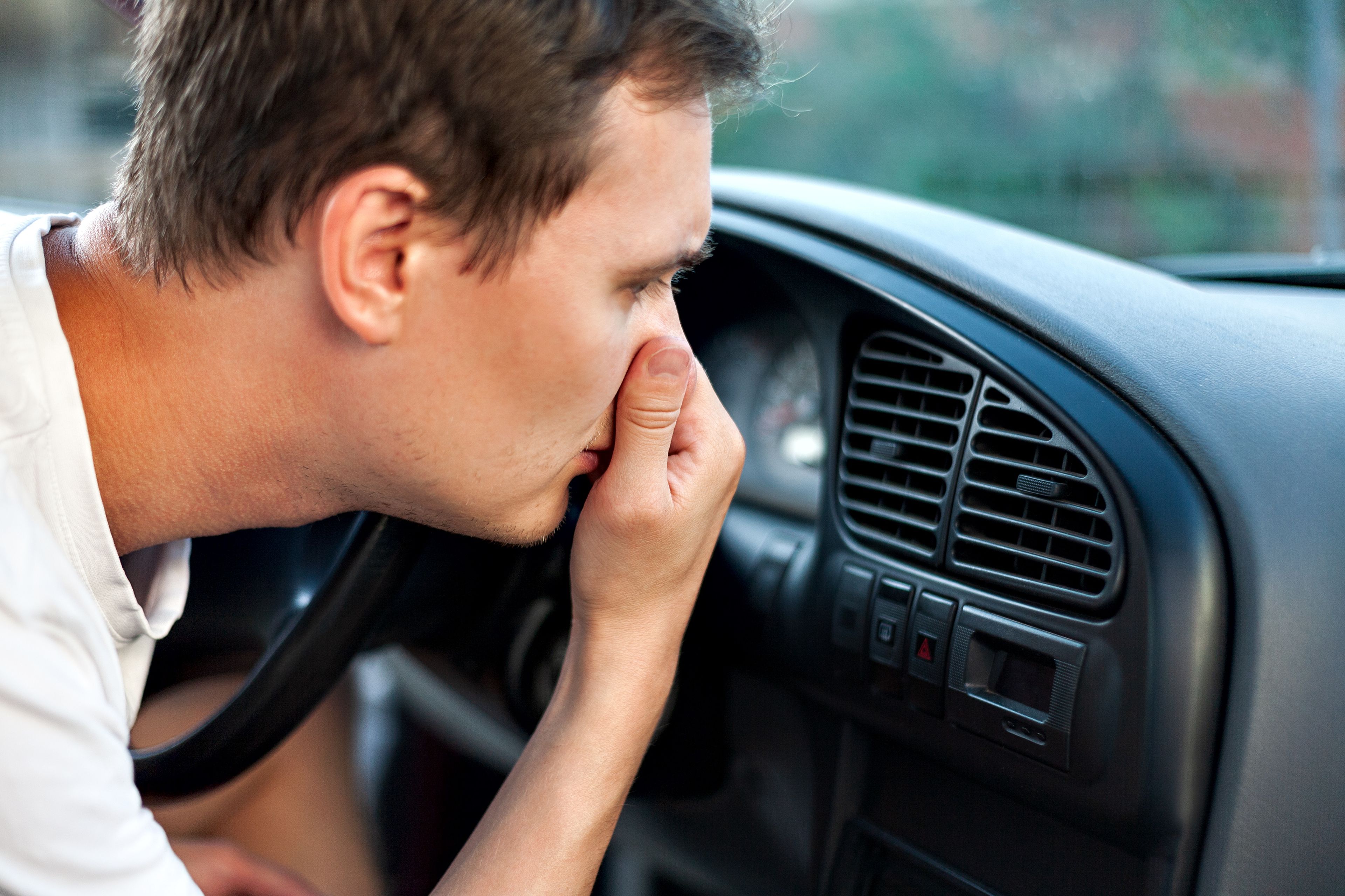 Hombre tapándose la nariz frente al aire acondicionado del coche
