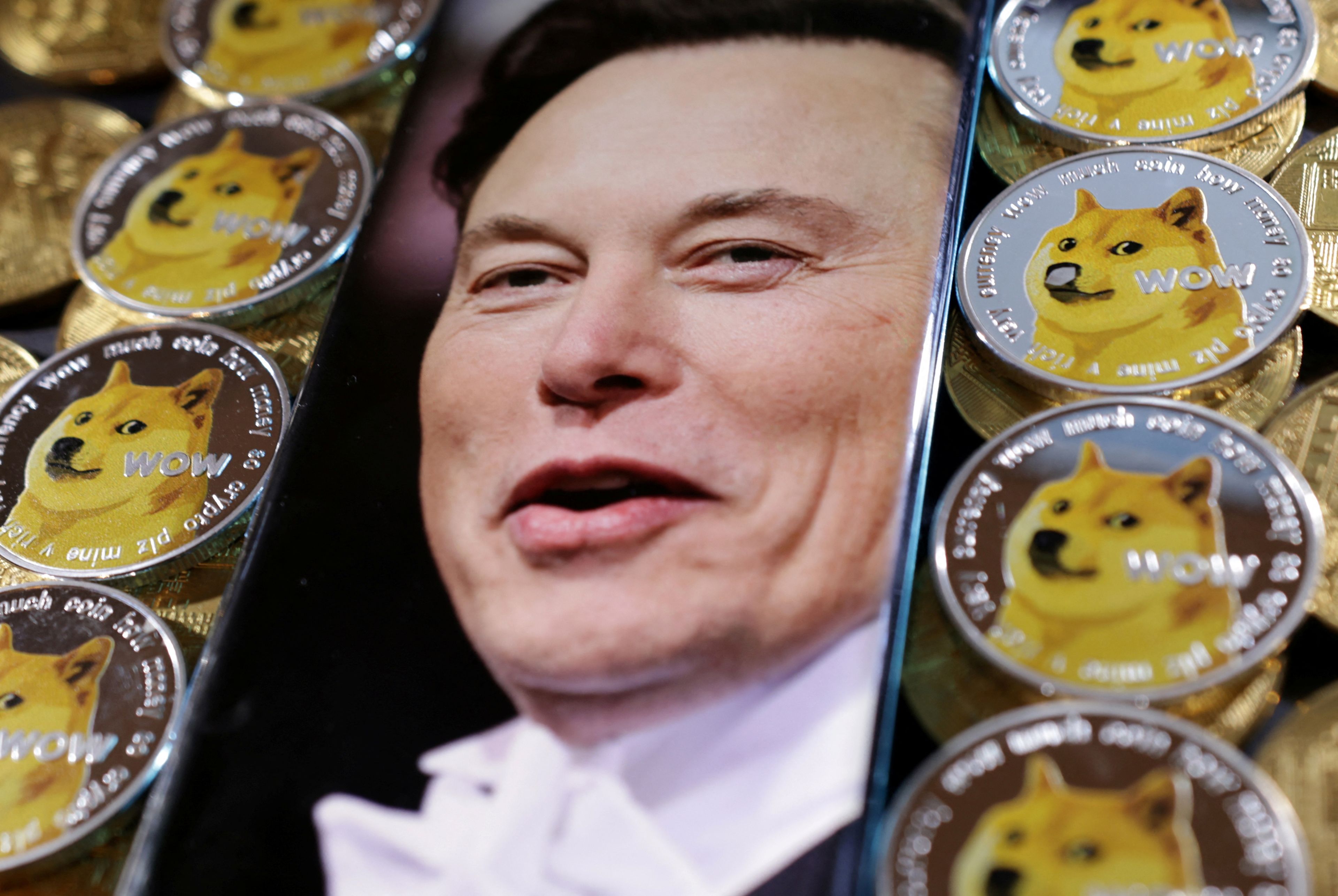 Ilustración con la cara de Elon Musk en un teléfono y varias monedas de dogecoin.