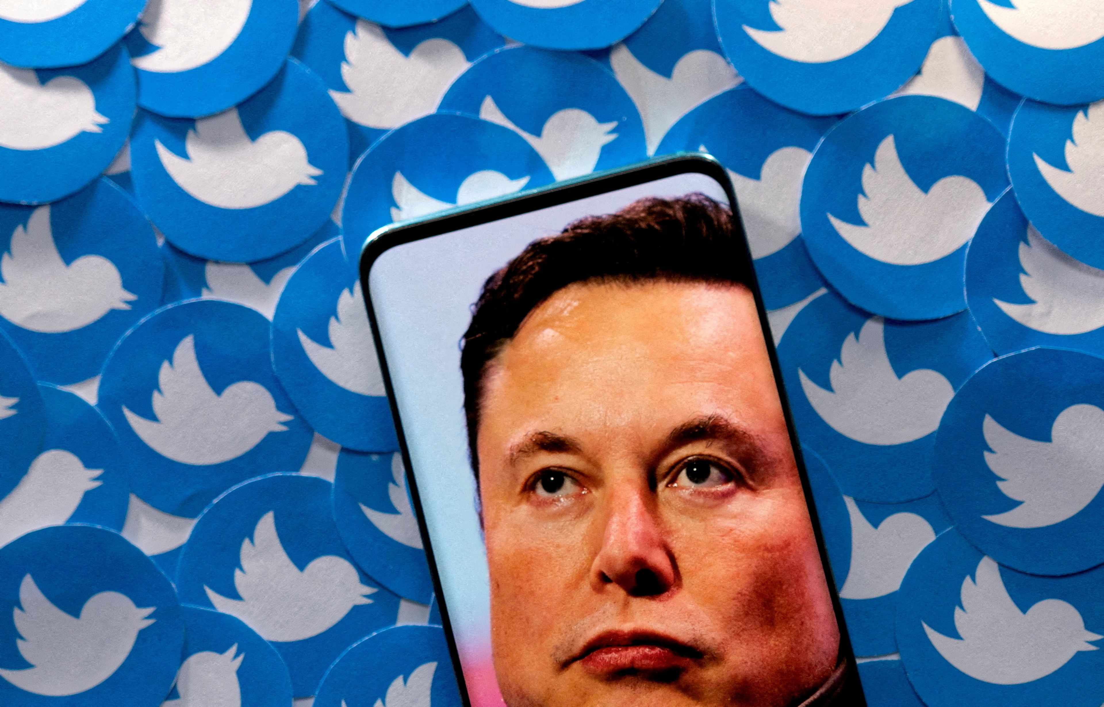 Ilustración con la imagen de Elon Musk en un teléfono móvil sobre el logotipo de Twitter repetido.