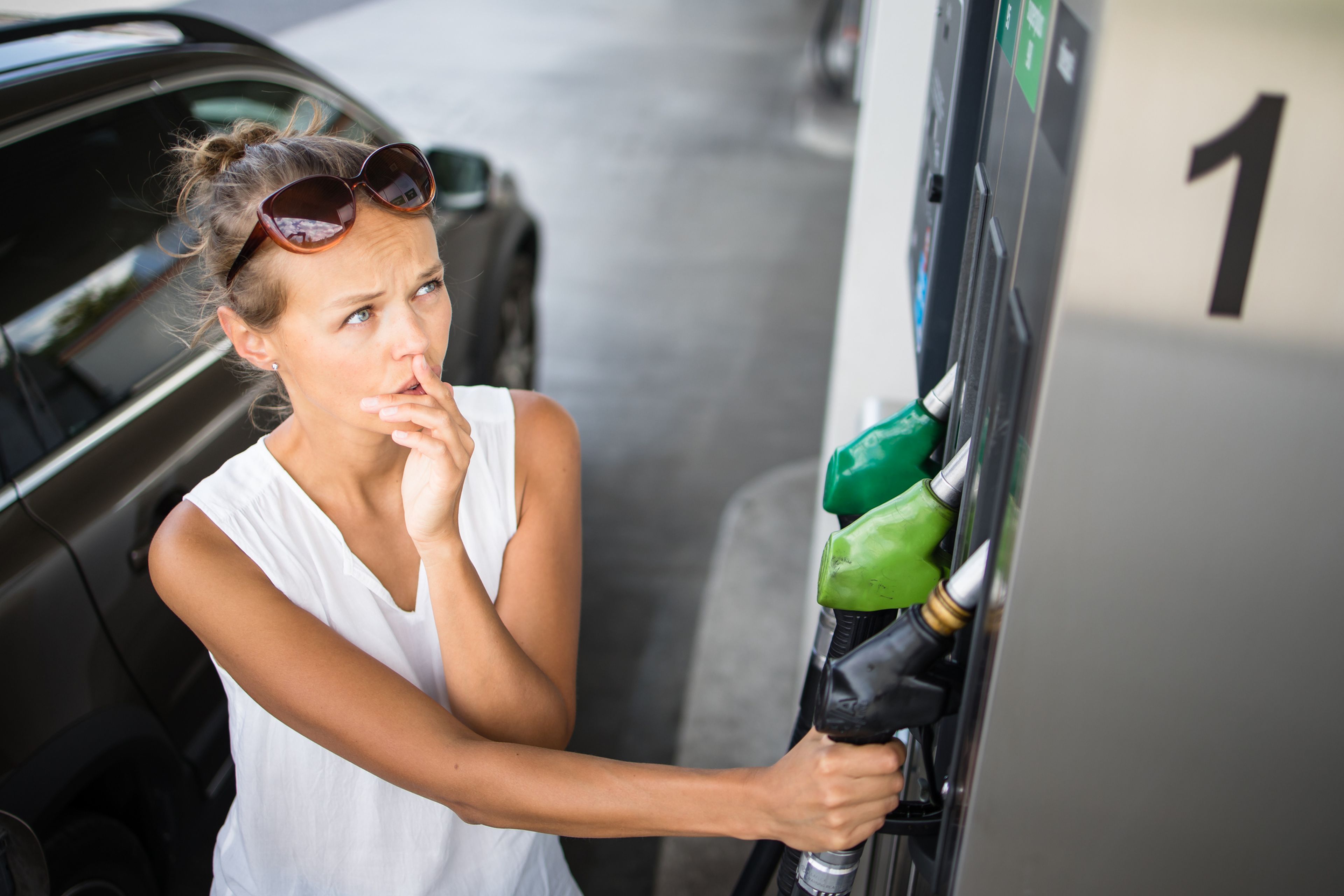 Una joven pensativa va a repostar el coche en una gasolinera
