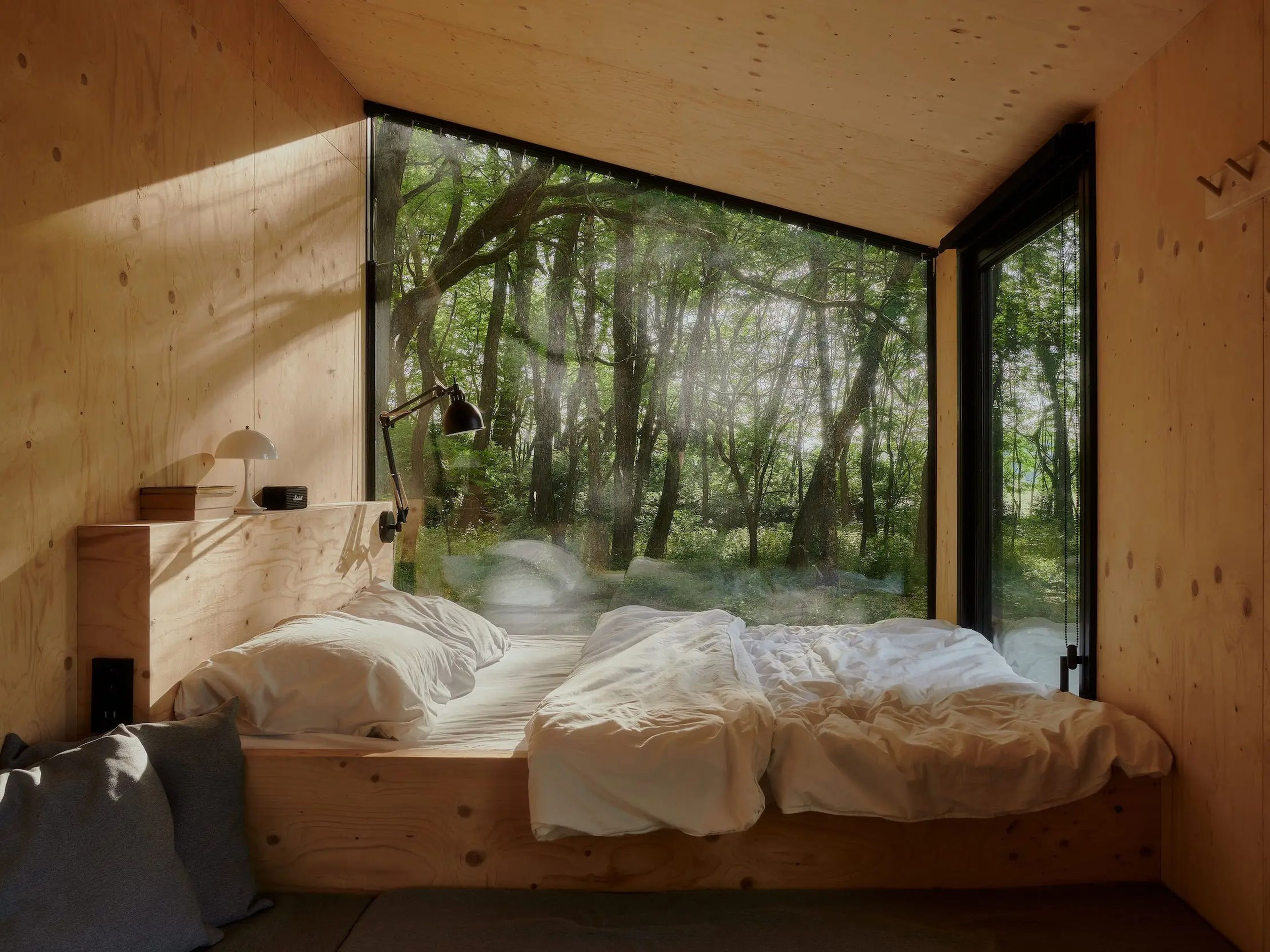 Una vista del interior de una cabaña de Raus con una cama cerca de las ventanas.