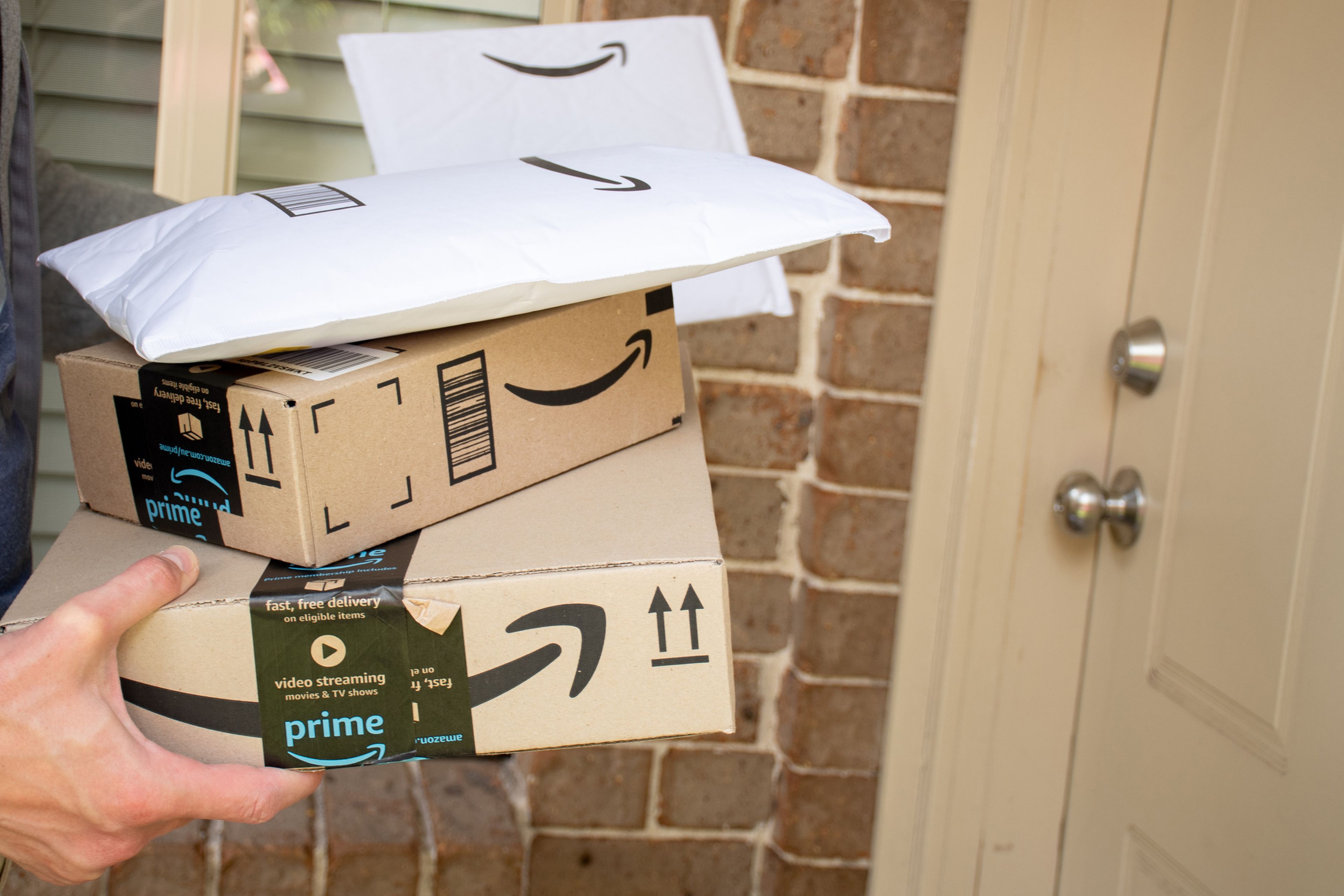 Una mano entregando unos paquetes de Amazon