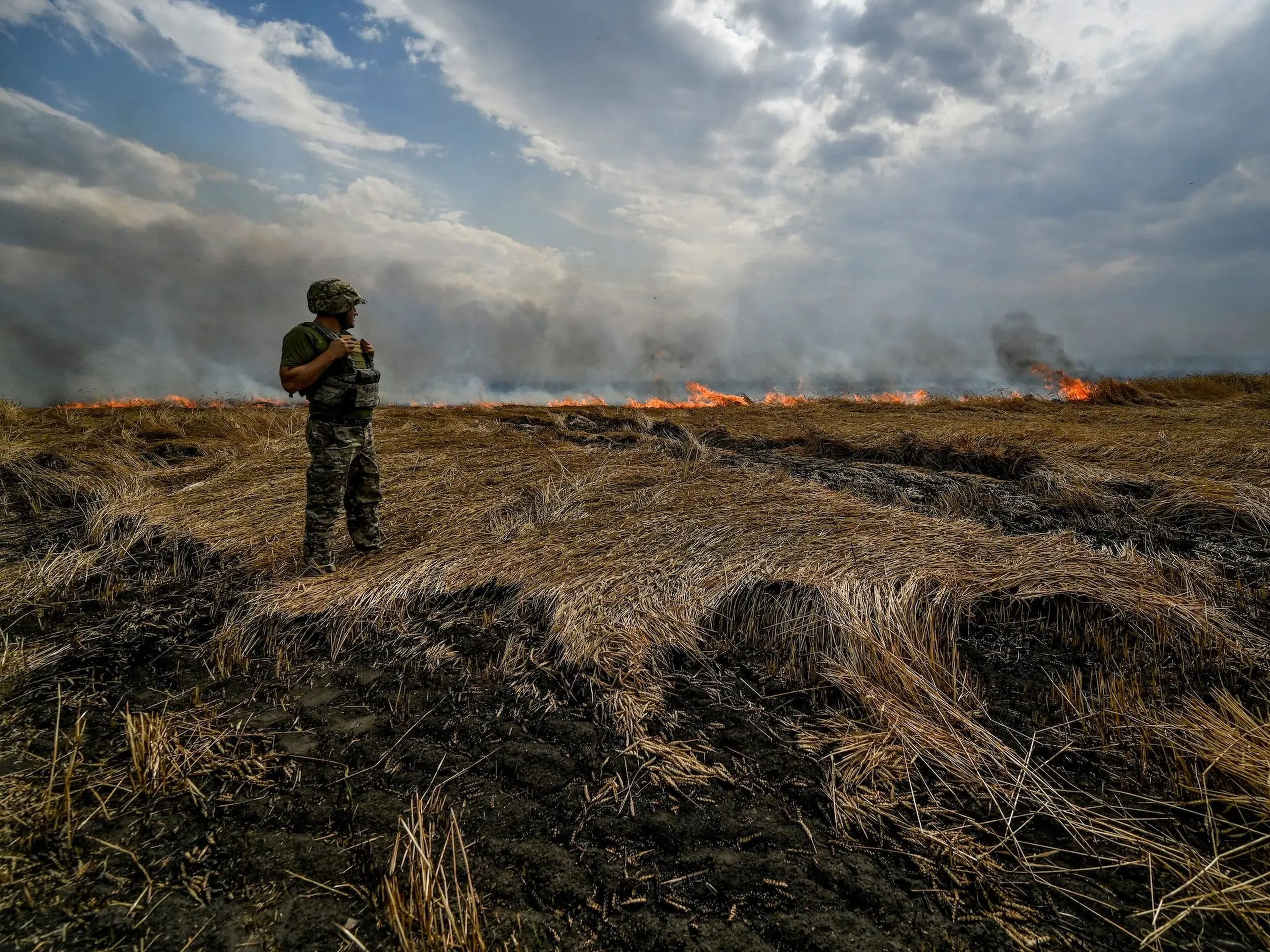 Un miembro del servicio ucraniano sobre un campo de trigo en llamas cerca de la línea del frente, en la frontera entre las regiones de Zaporizhzhia y Donetsk, durante el ataque de Rusia a Ucrania el 17 de julio.