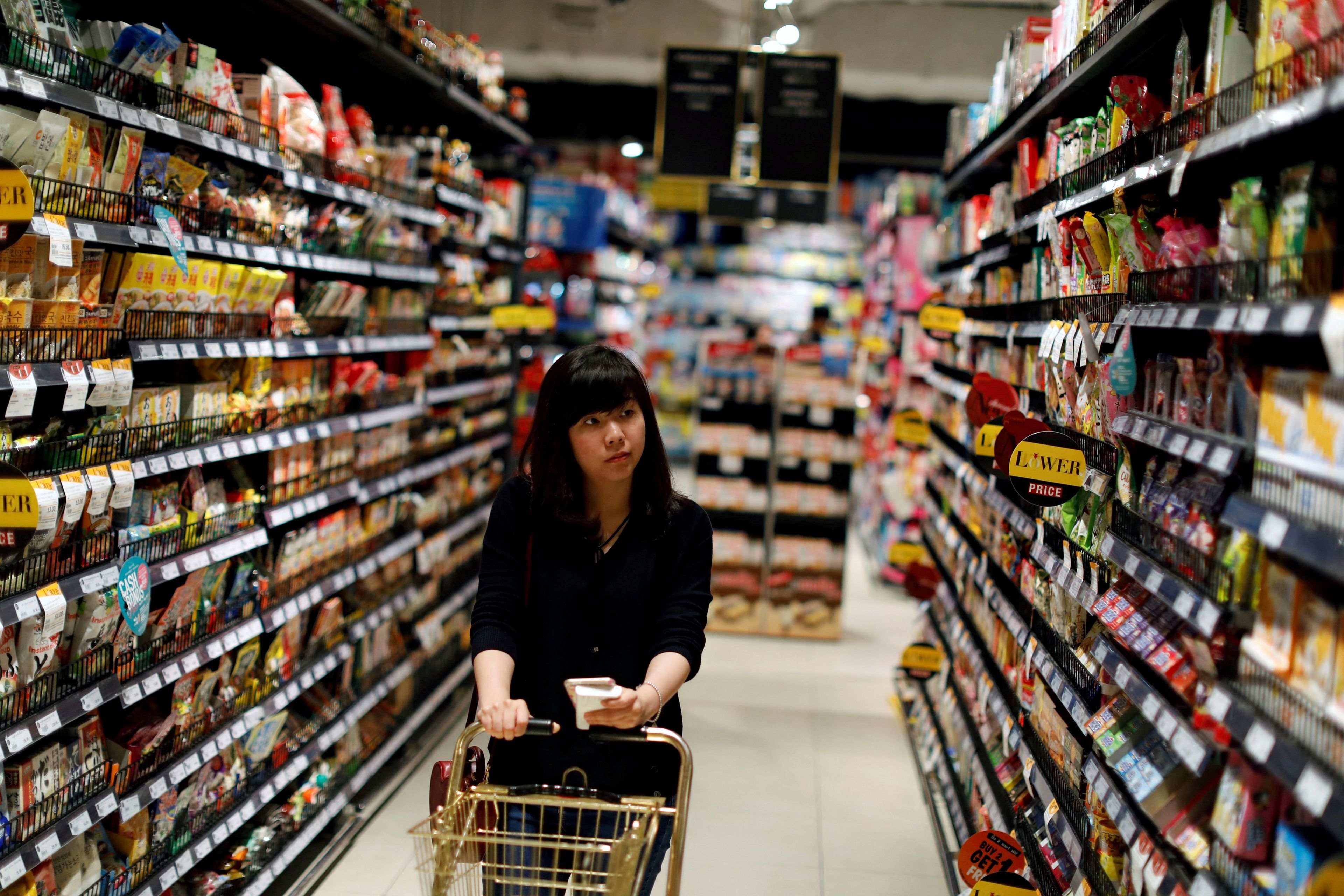 Una mujer paseándose por un pasillo del supermercado.