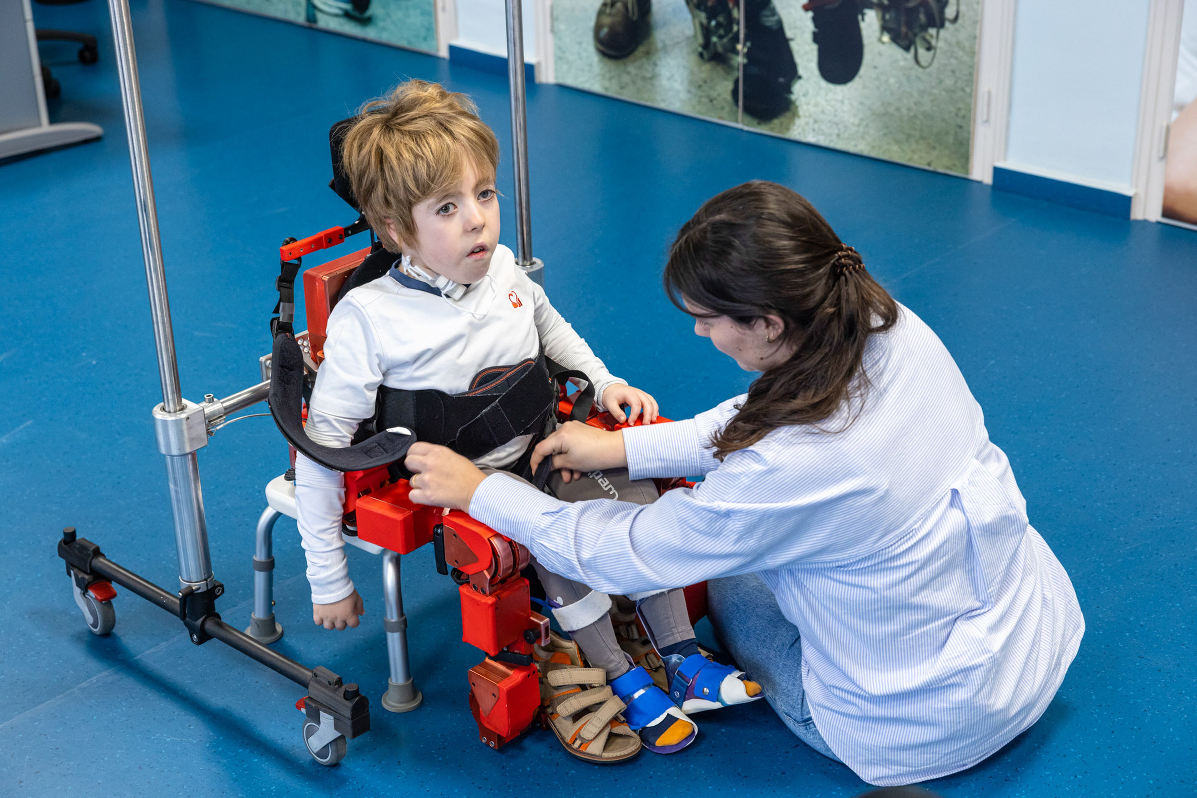 Un niño al que le están ajustando el exoesqueleto pediátrico adaptable.