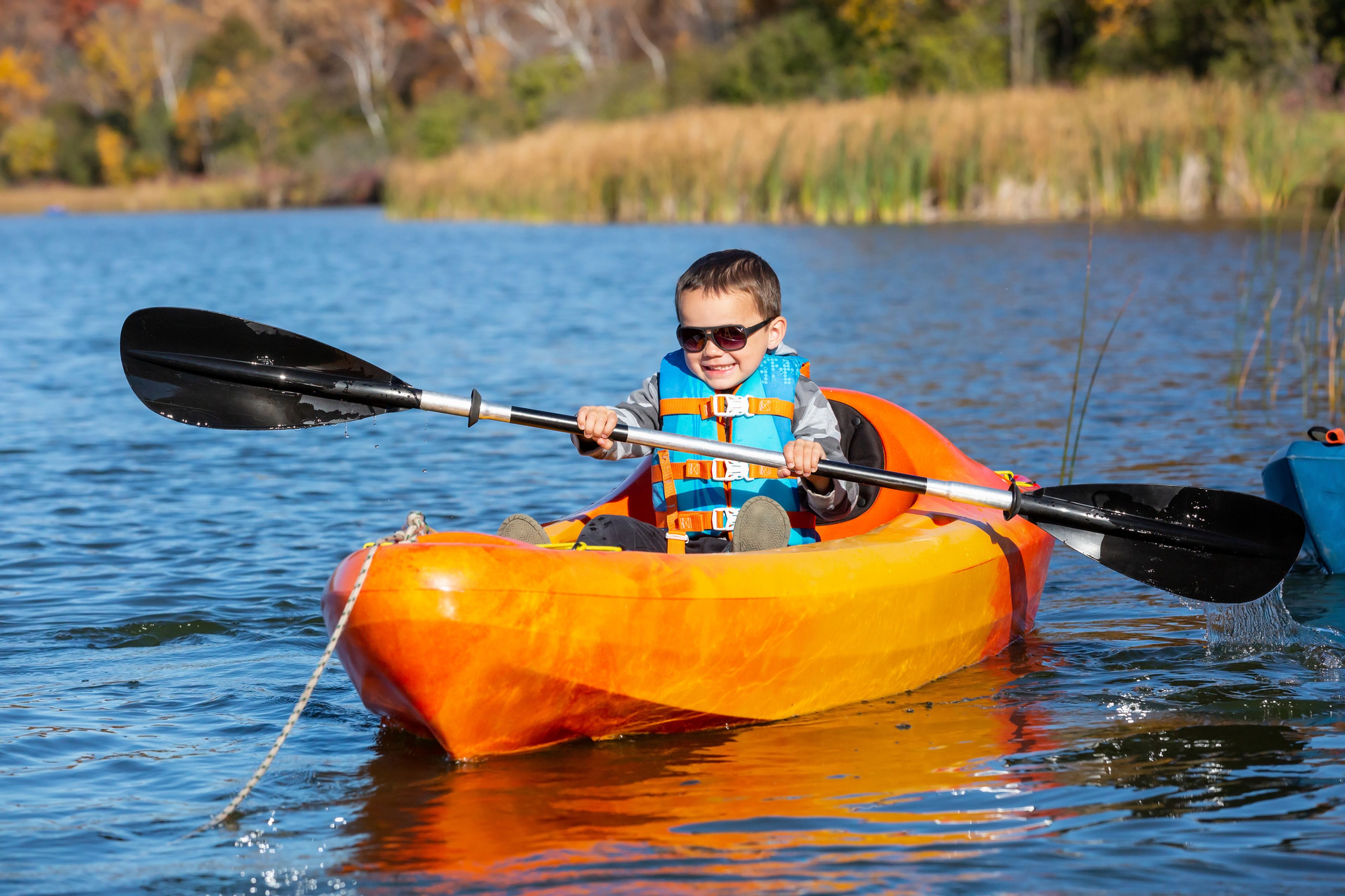 Niño pequeño en un kayak en un lago, en verano