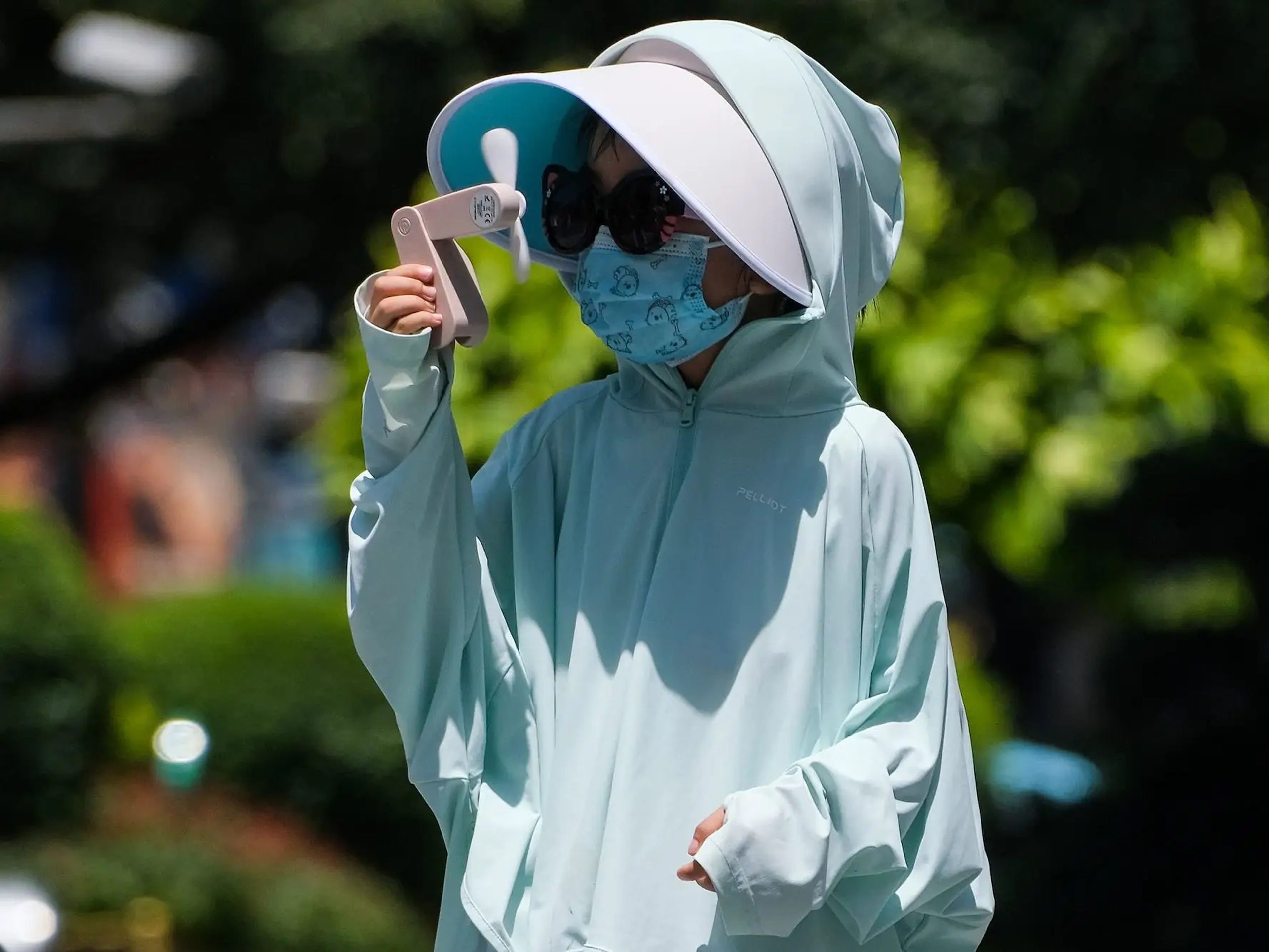 Un niño con ropa de protección solar se refresca con un ventilador eléctrico portátil el 14 de julio de 2022 en Chongqing, China.
