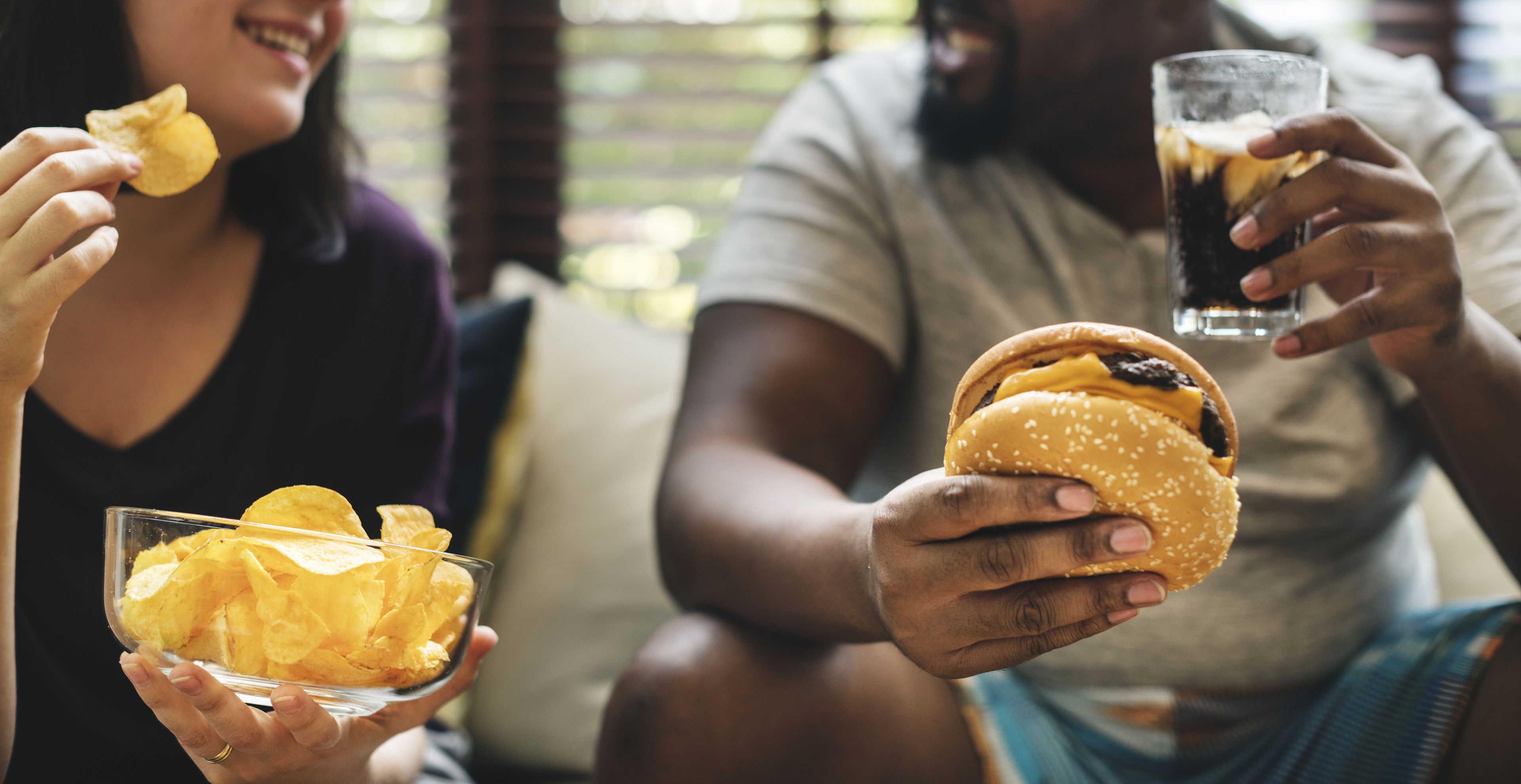 Una pareja come hamburguesas y patatas fritas.