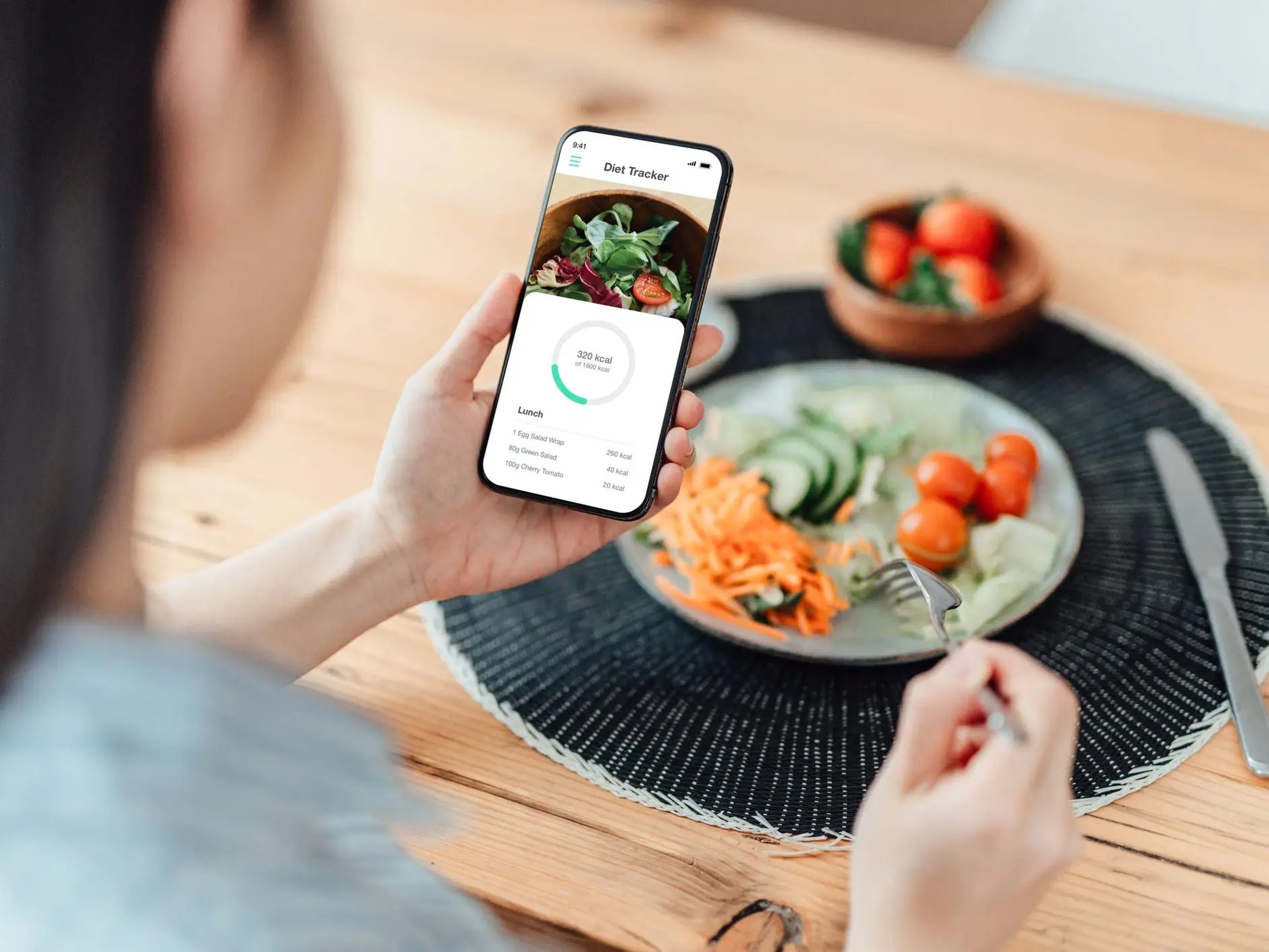 a person looking at a food tracking diet app next to a plate of salad