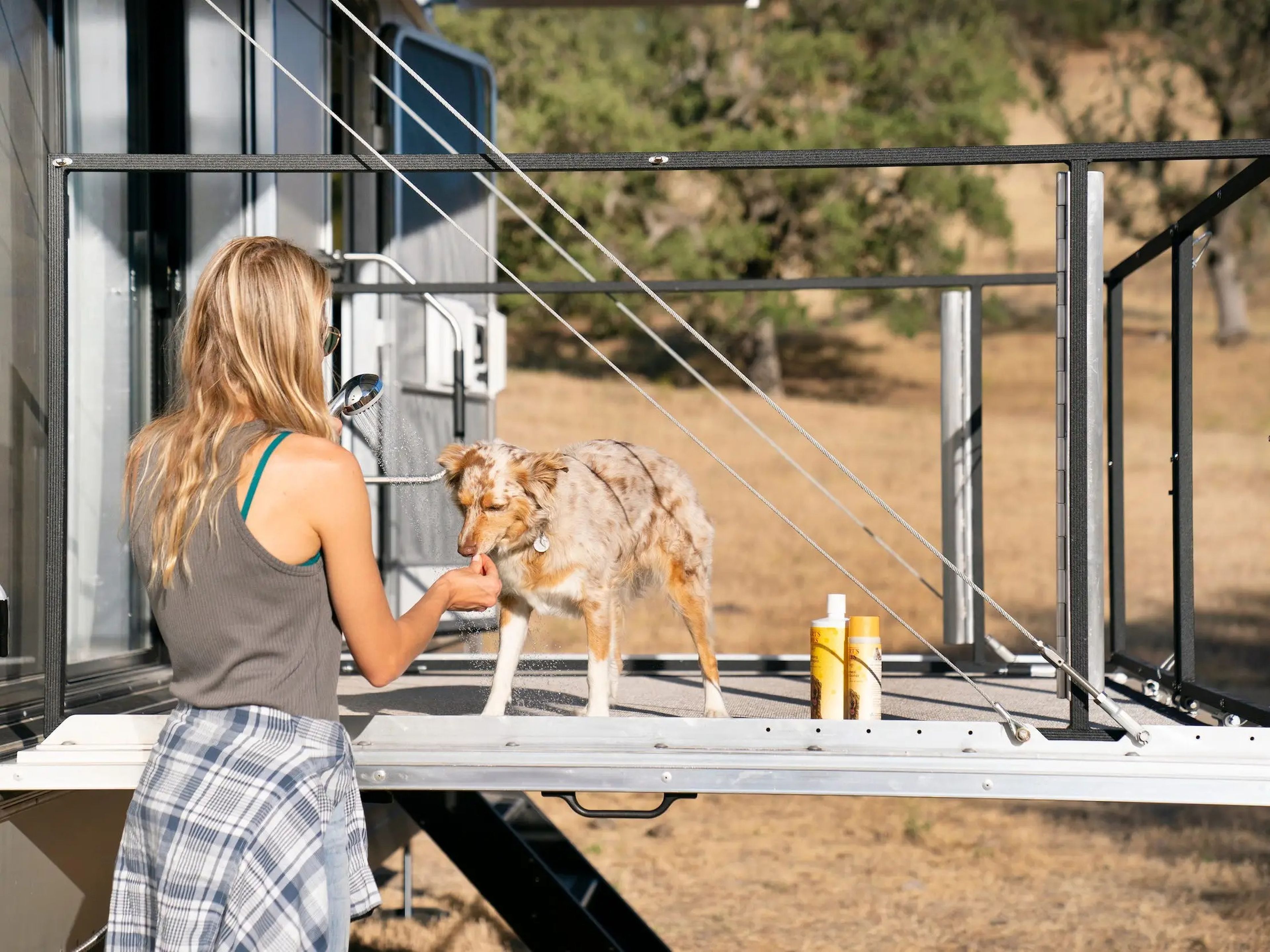 A person washing a dog on the travel trailer's deck