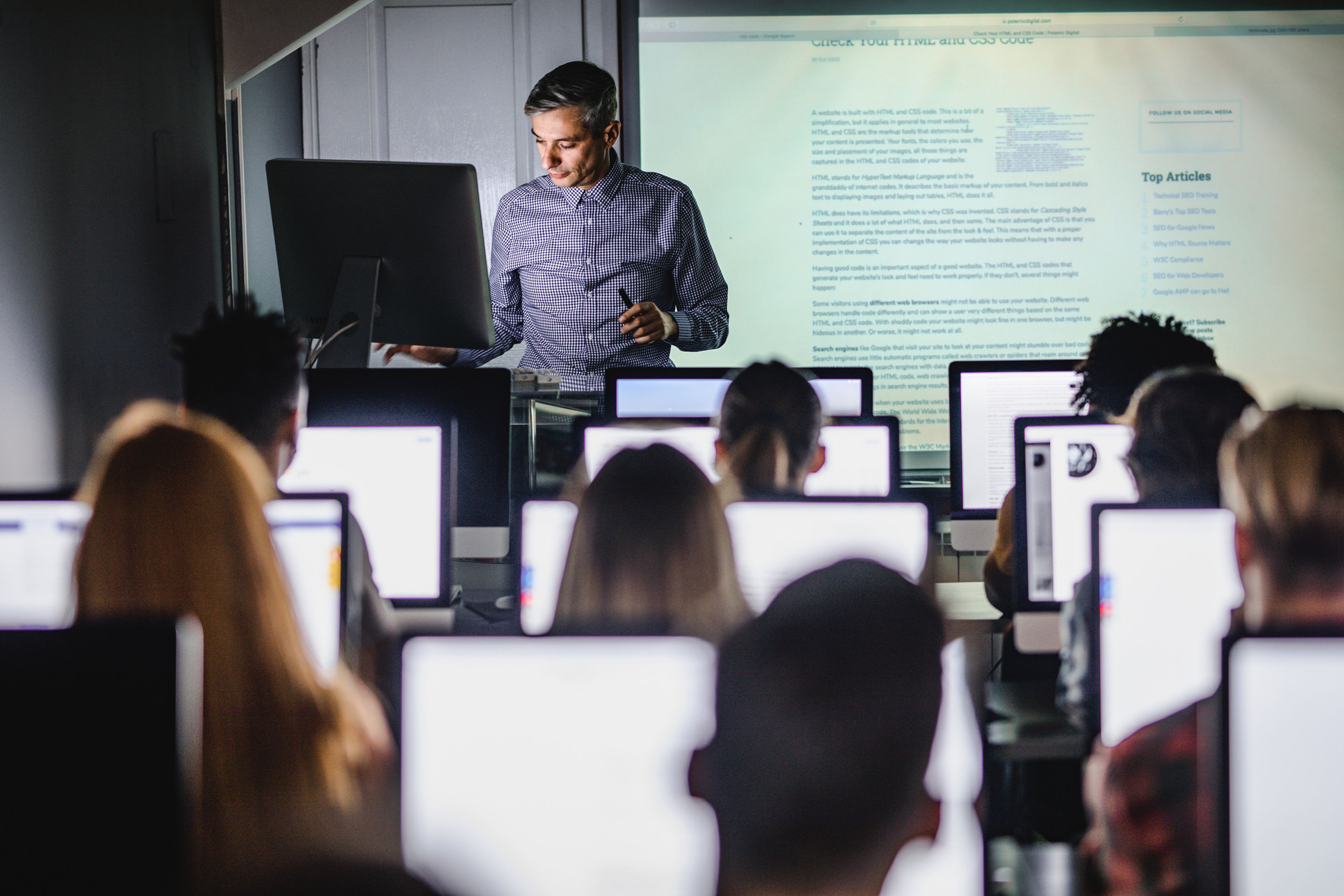 Un profesor dando clase en un aula con ordenadores.