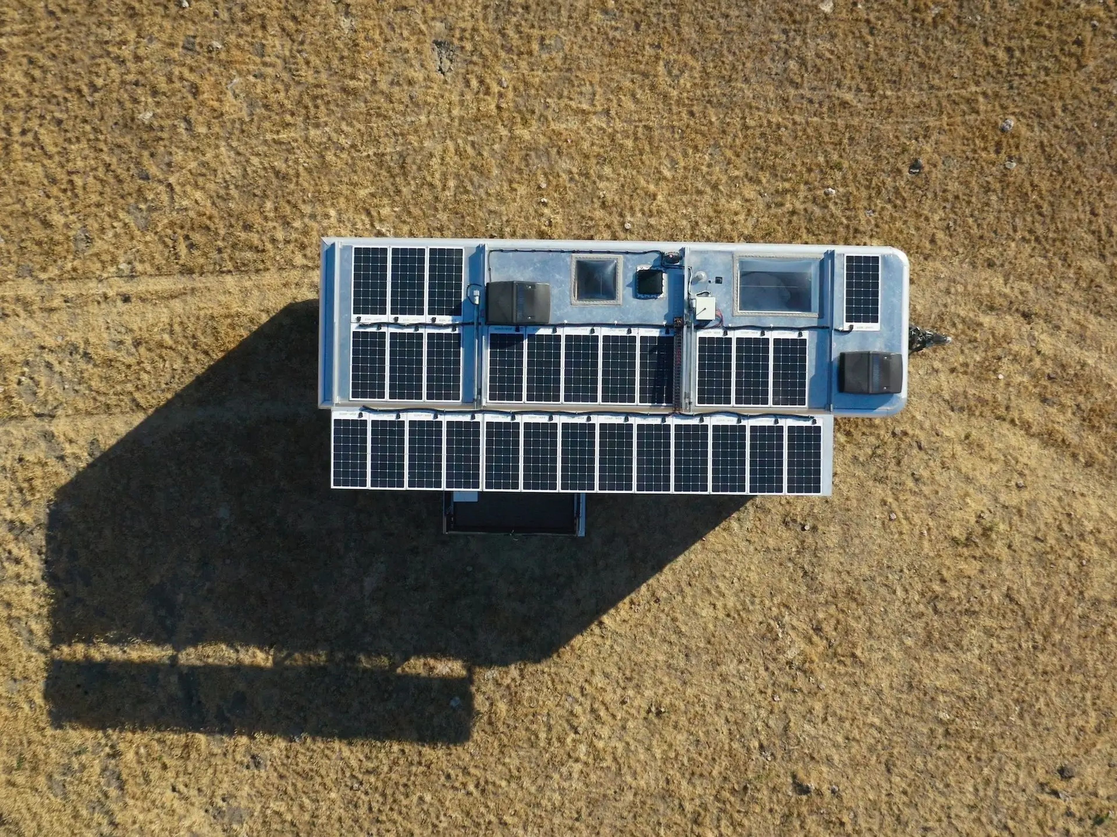 The solar panels on top of the travel trailer as the trailer sits on a field.