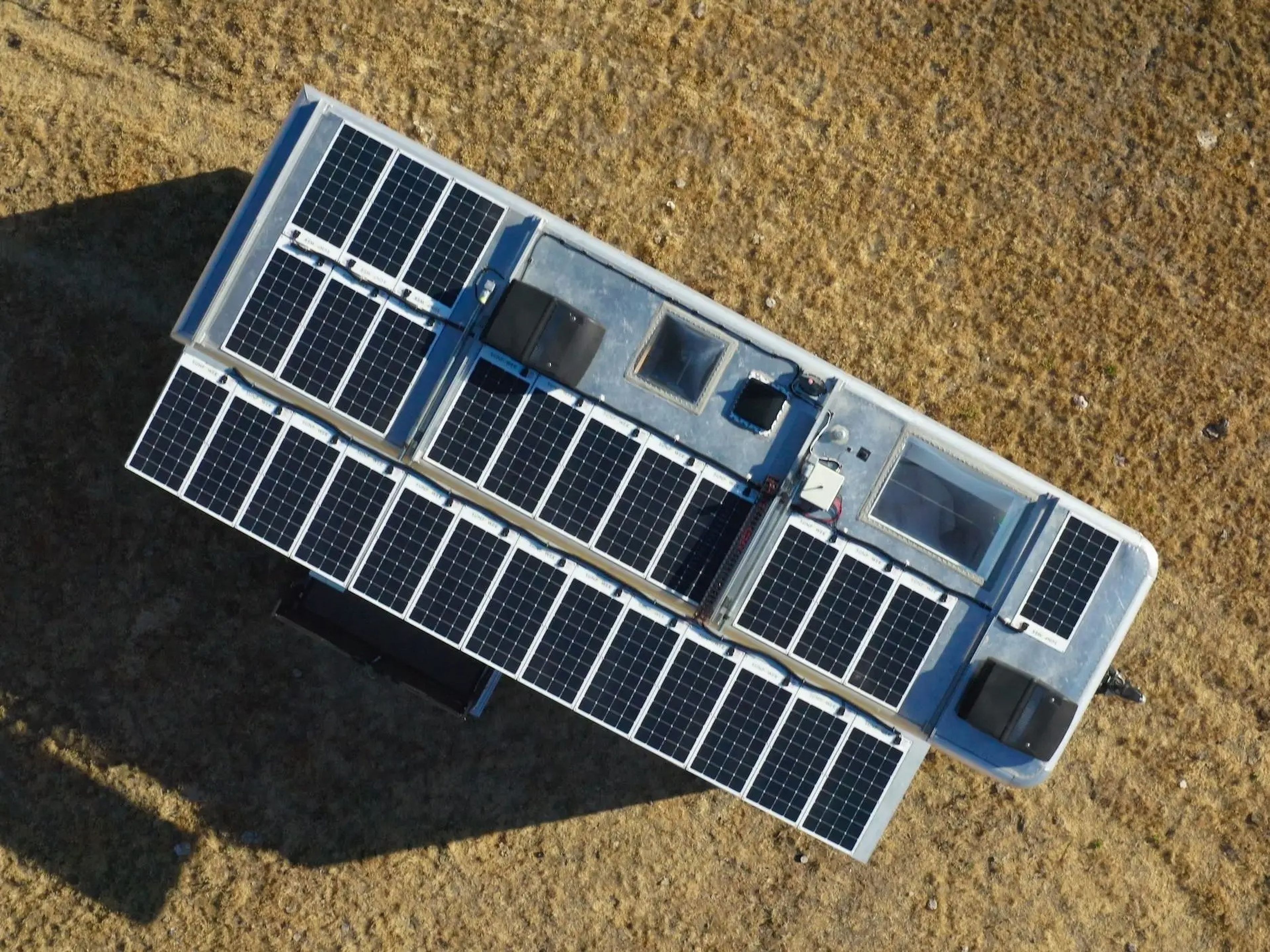 The solar panels on top of the travel trailer as the trailer sits on a field.