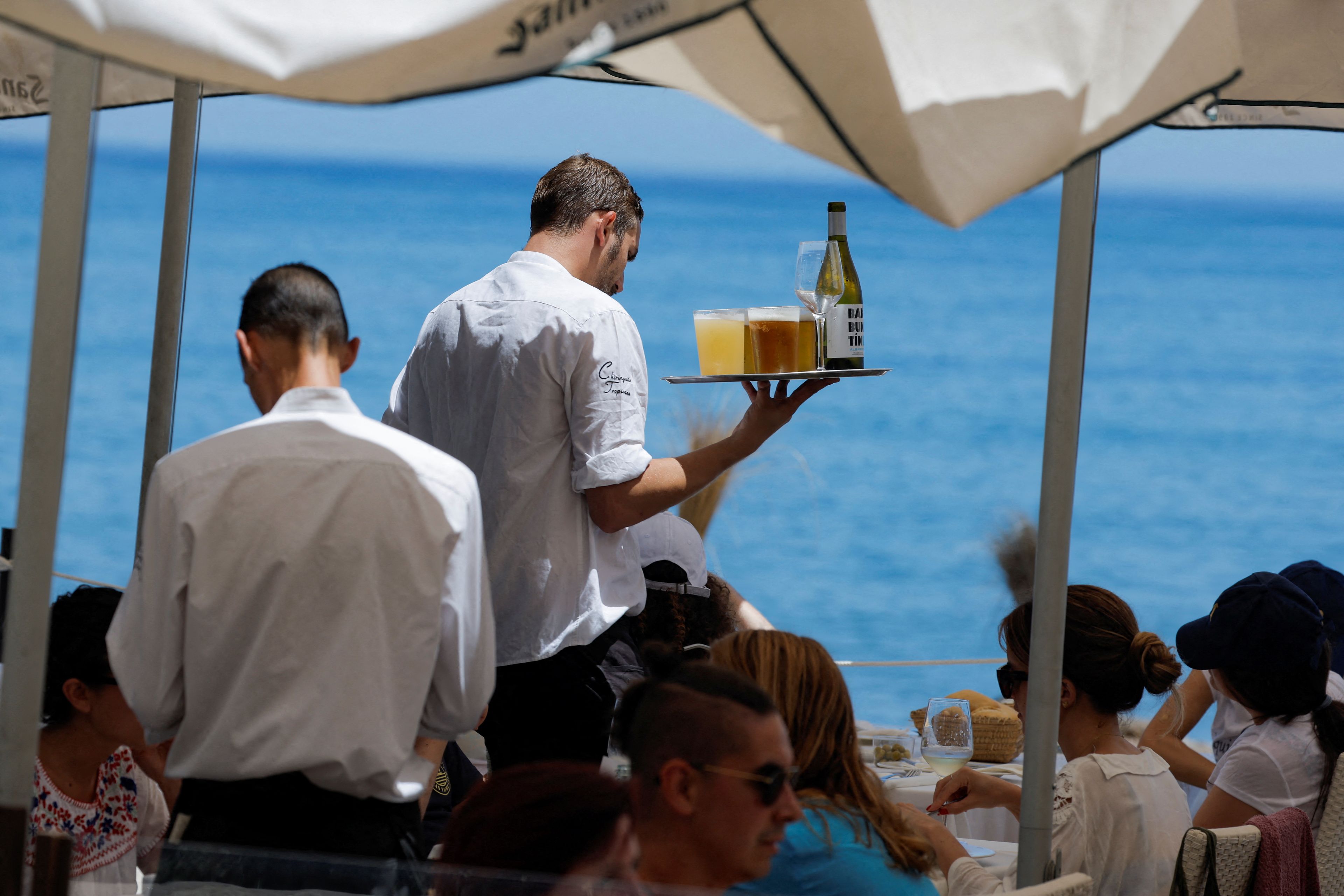 Un camarero sirve en la terraza de un bar en Málaga, en verano.